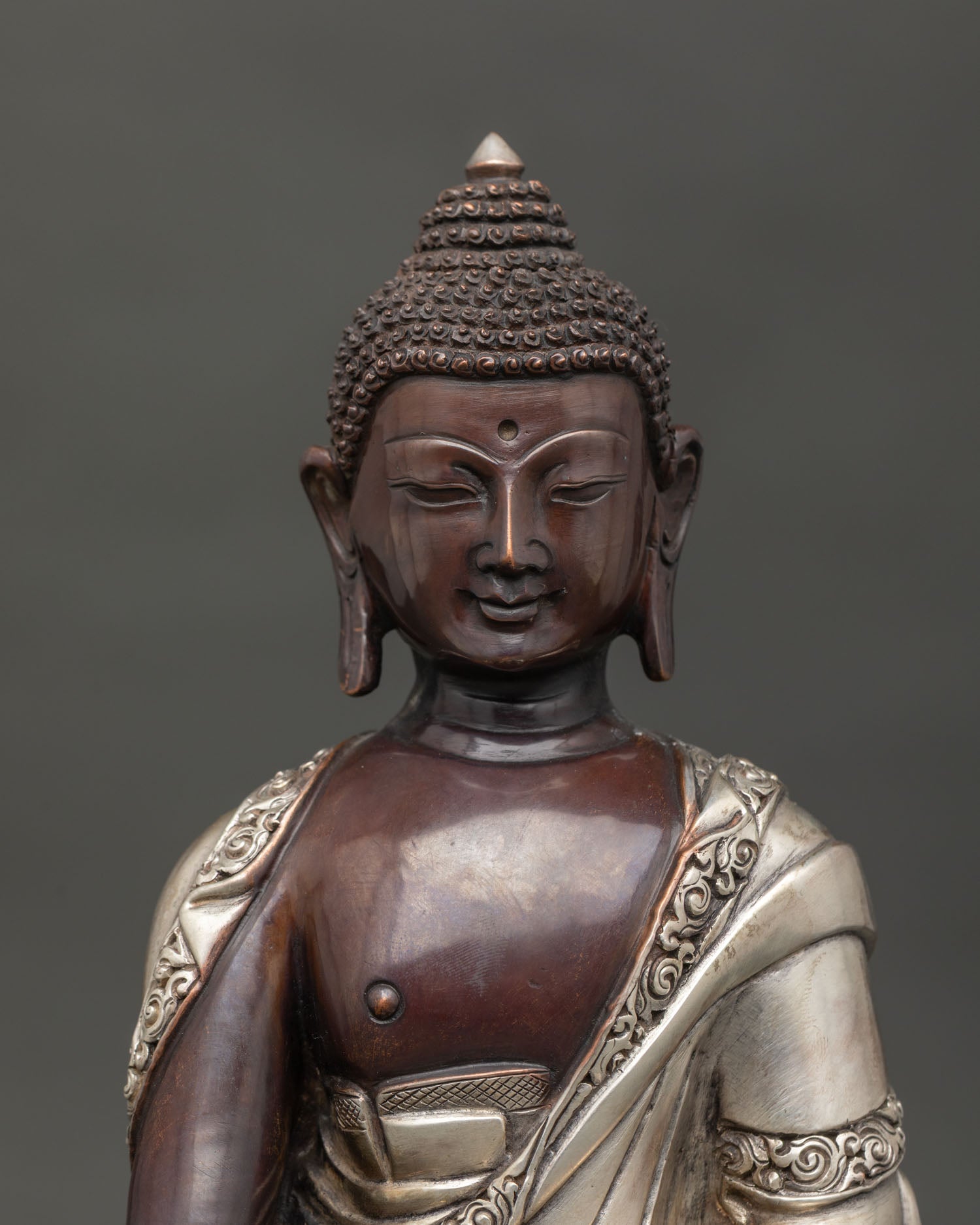 Handmade Shakyamuni Buddha statue from Nepal with silver plated monk robe close up.
