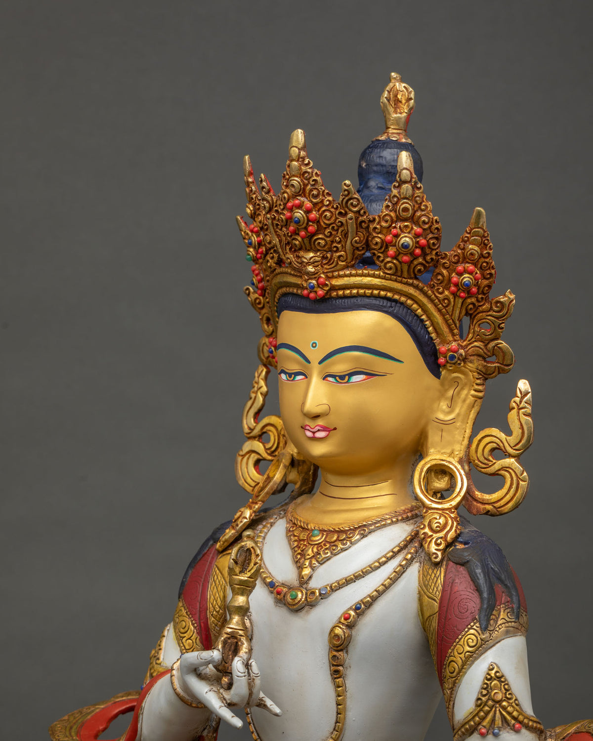 Side close-up of Vajrasattva statue showing crown detail and lotus pedestal