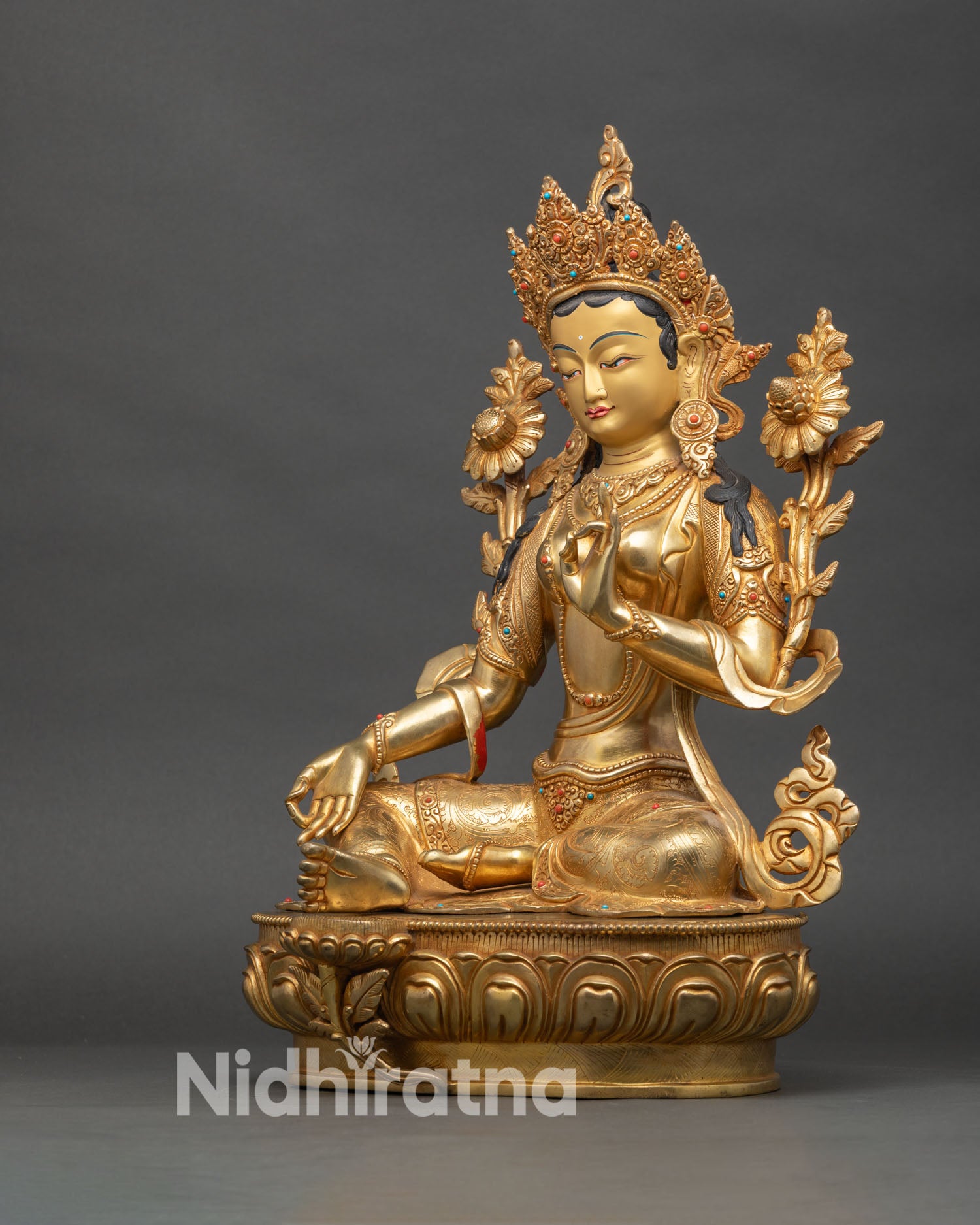 Left profile of Green Tara statue, lotus blossoms, intricate gold detailing