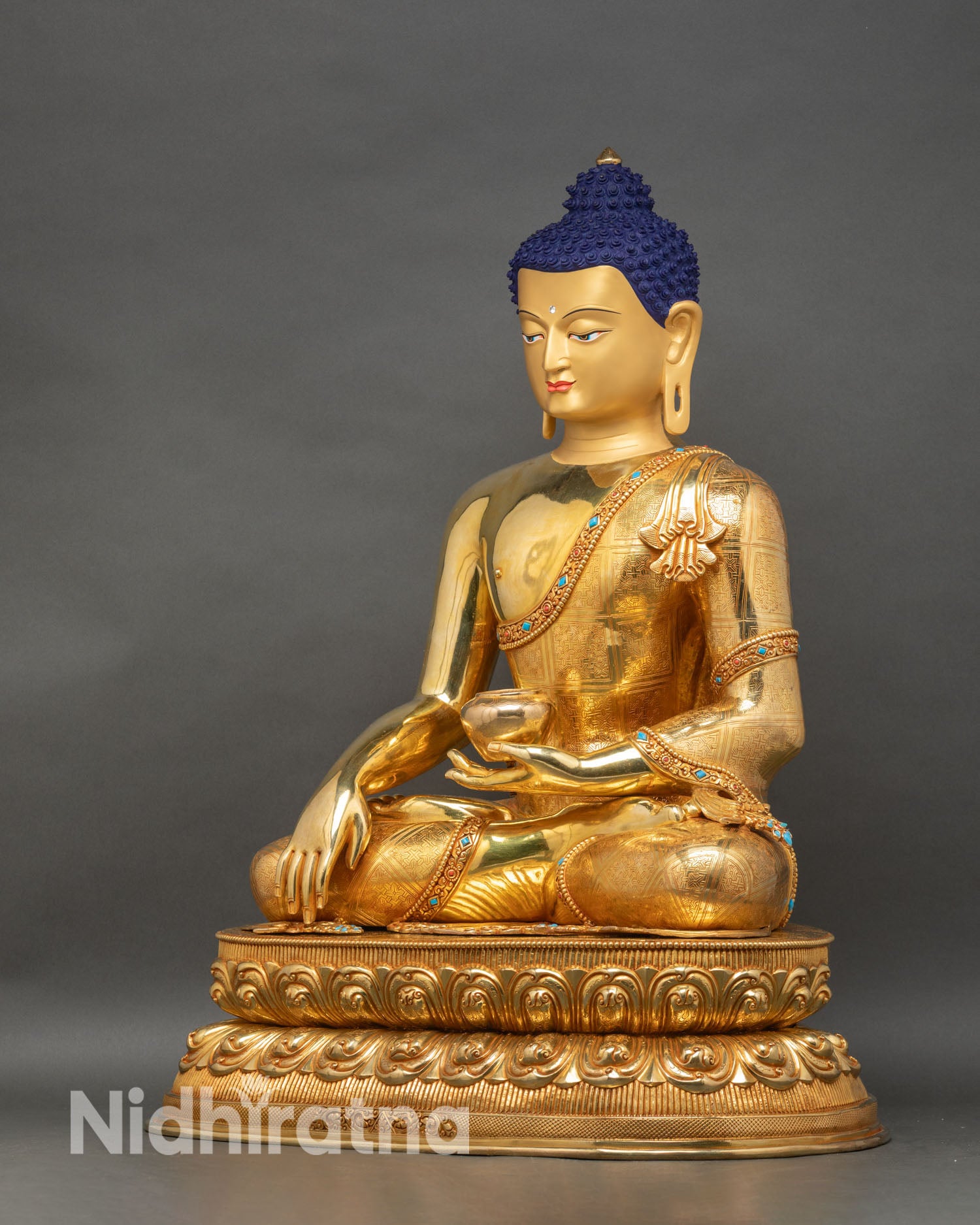 Left profile of Shakyamuni Buddha statue, seated on double-layered lotus, detailed ceremonial robe