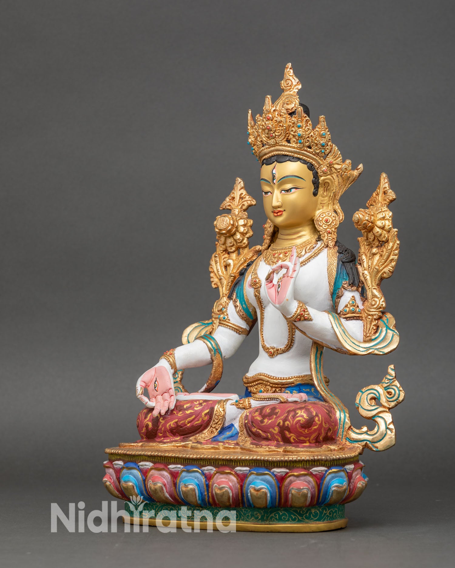 left profile of white tara statue, white-toned body with gold-gilded robes and crown