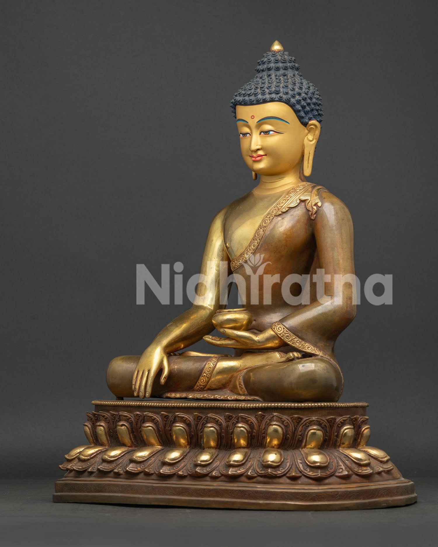 Left profile view of half gold fire-gilded Buddha statue holding alms bowl