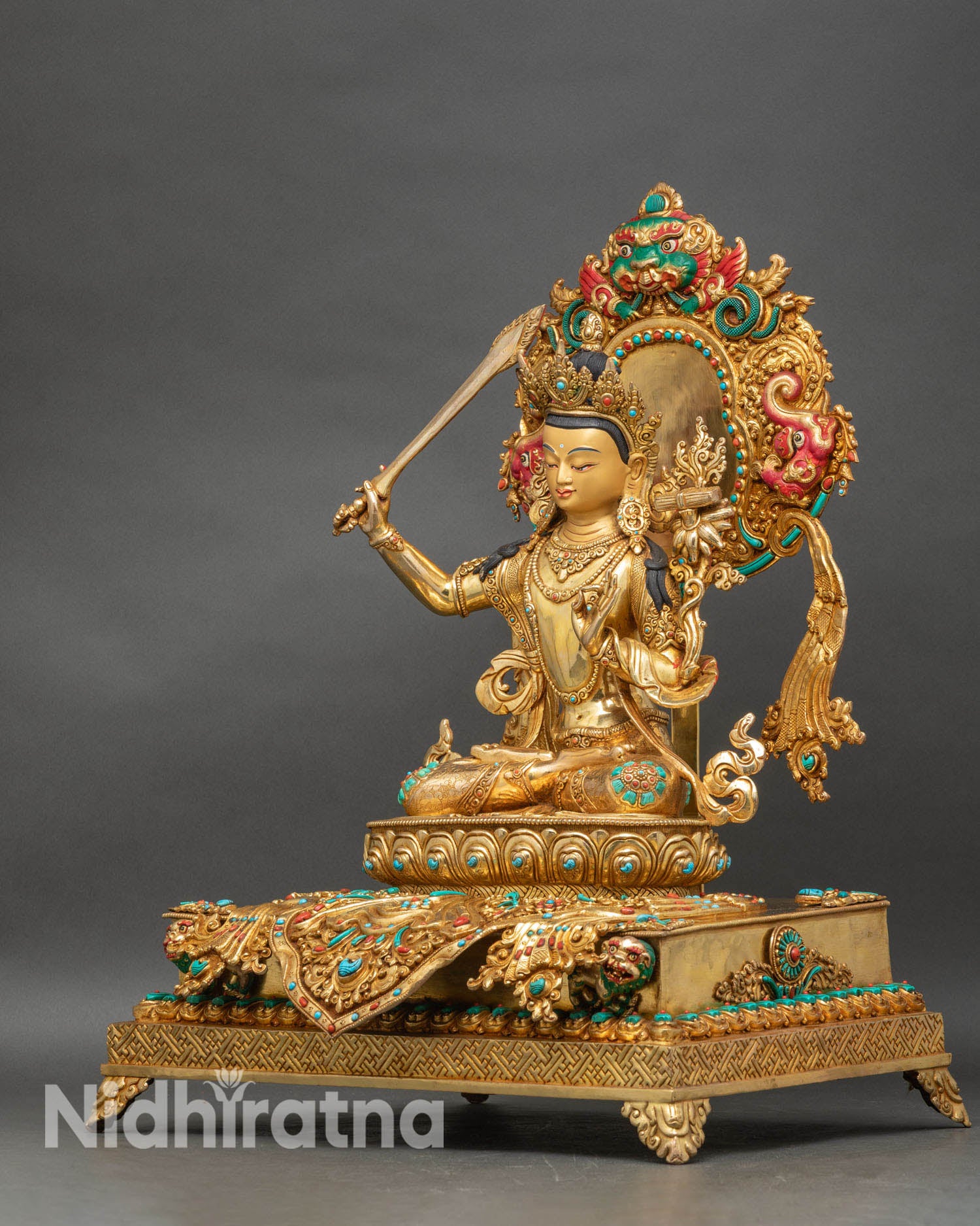 left profile of manjushri statue with lotus and scripture, gold fire-gilded copper
