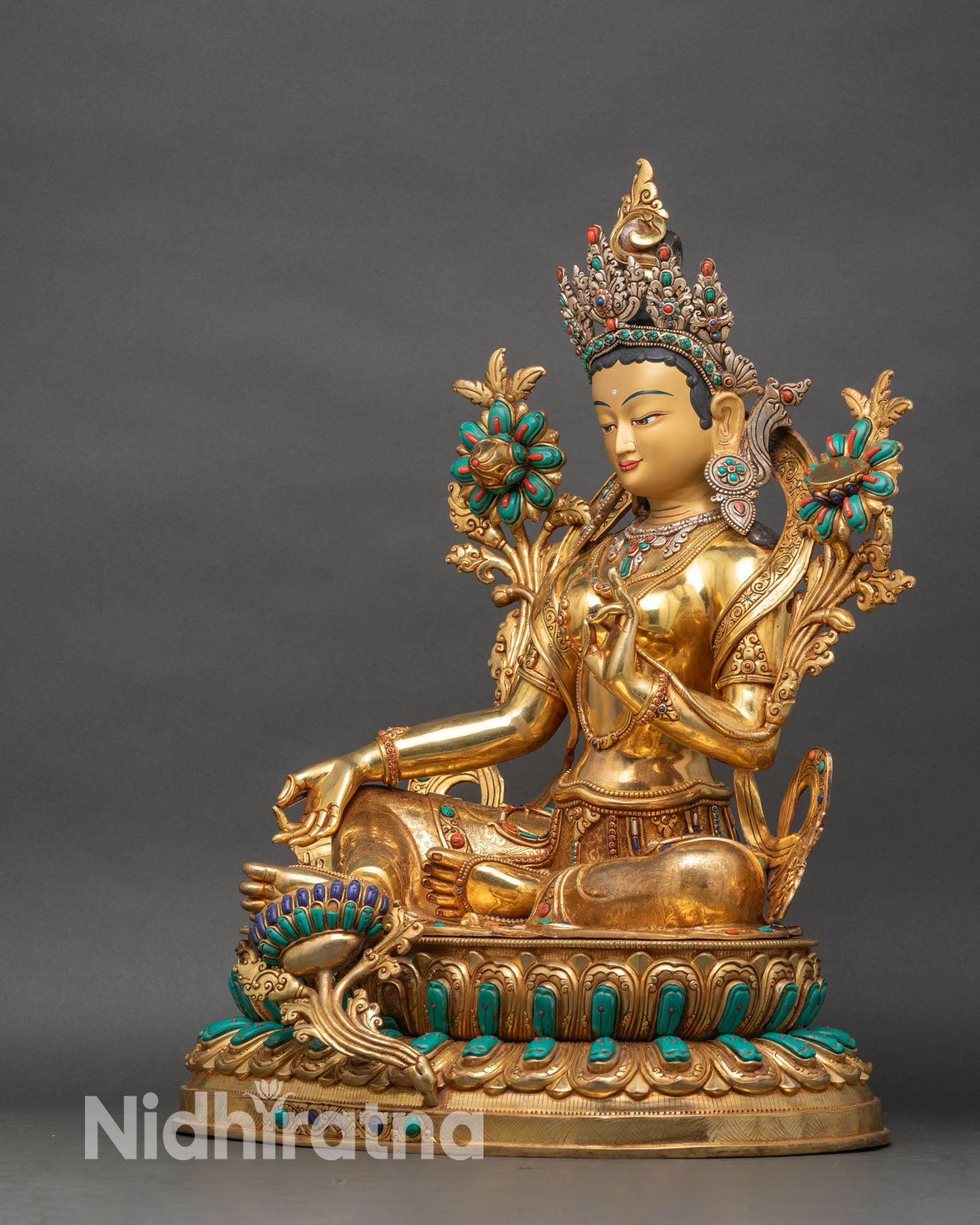 Left side view of Green Tara statue showing fire-gilded robes and double lotus base