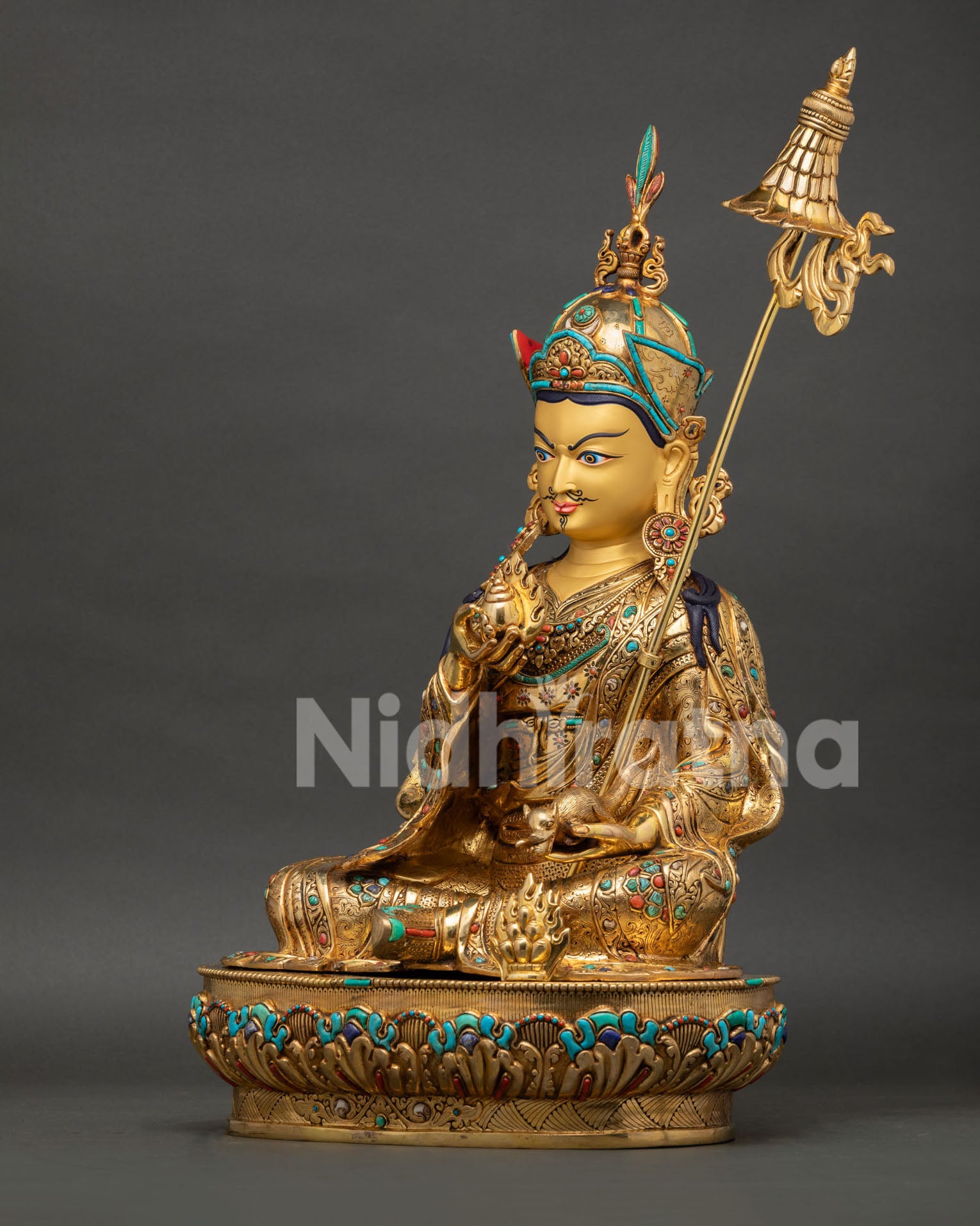 left side view of guru orgyen norlha wealth deity statue with khatvanga staff and sacred details