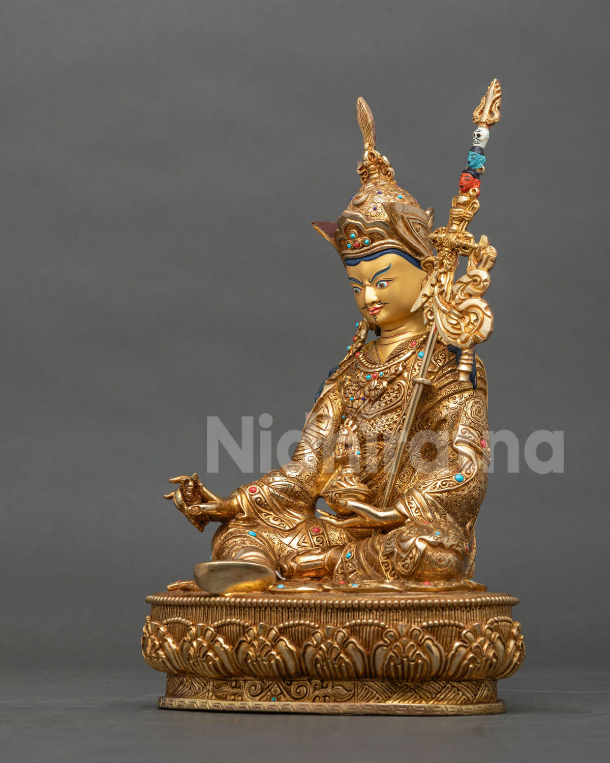 Left side view of Padmasambhava statue seated in royal posture on a lotus base, fire-gilded copper