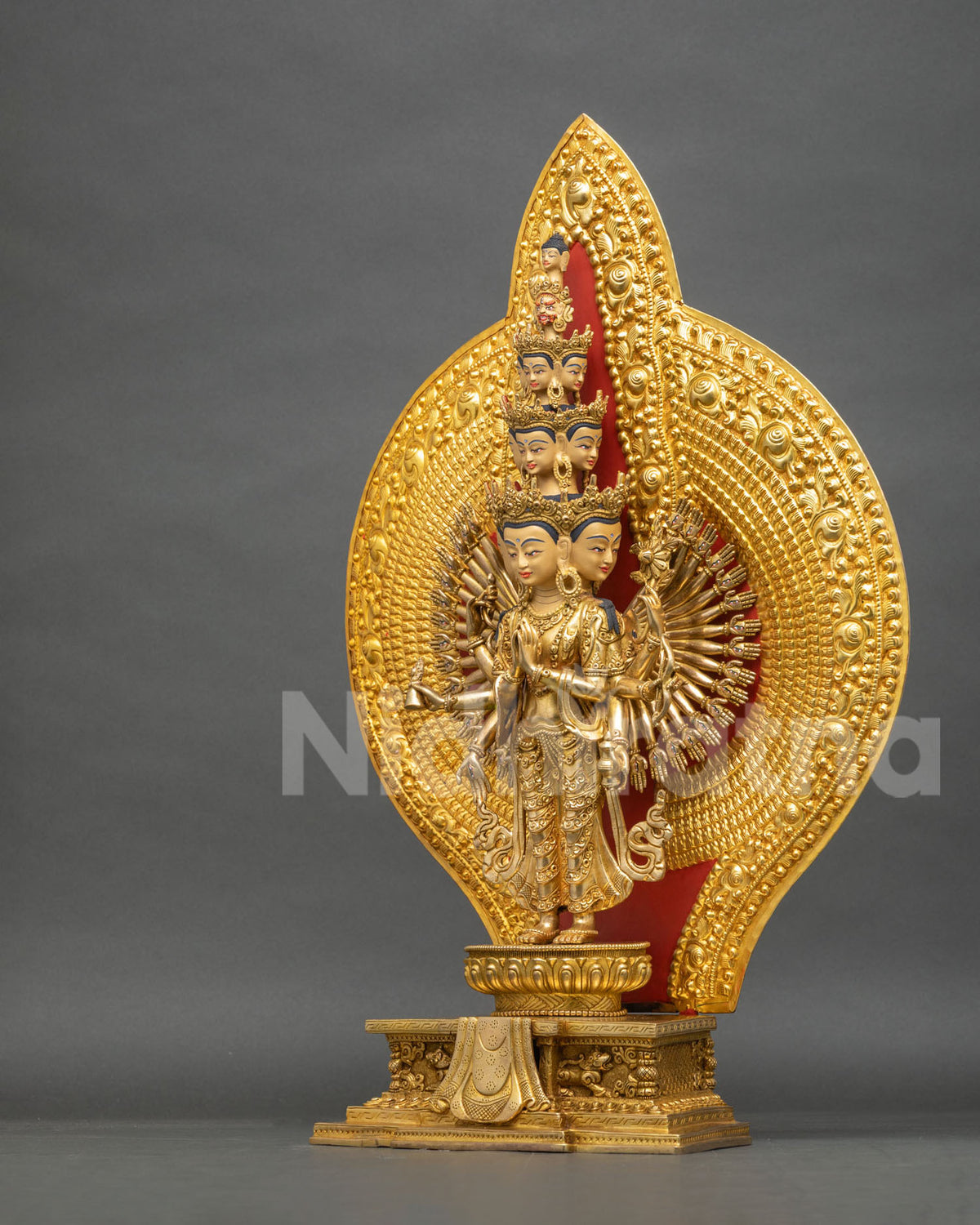 Left side view of Thousand Armed Chenrezig statue on lotus pedestal and lion throne, 24K gold fire-gilded