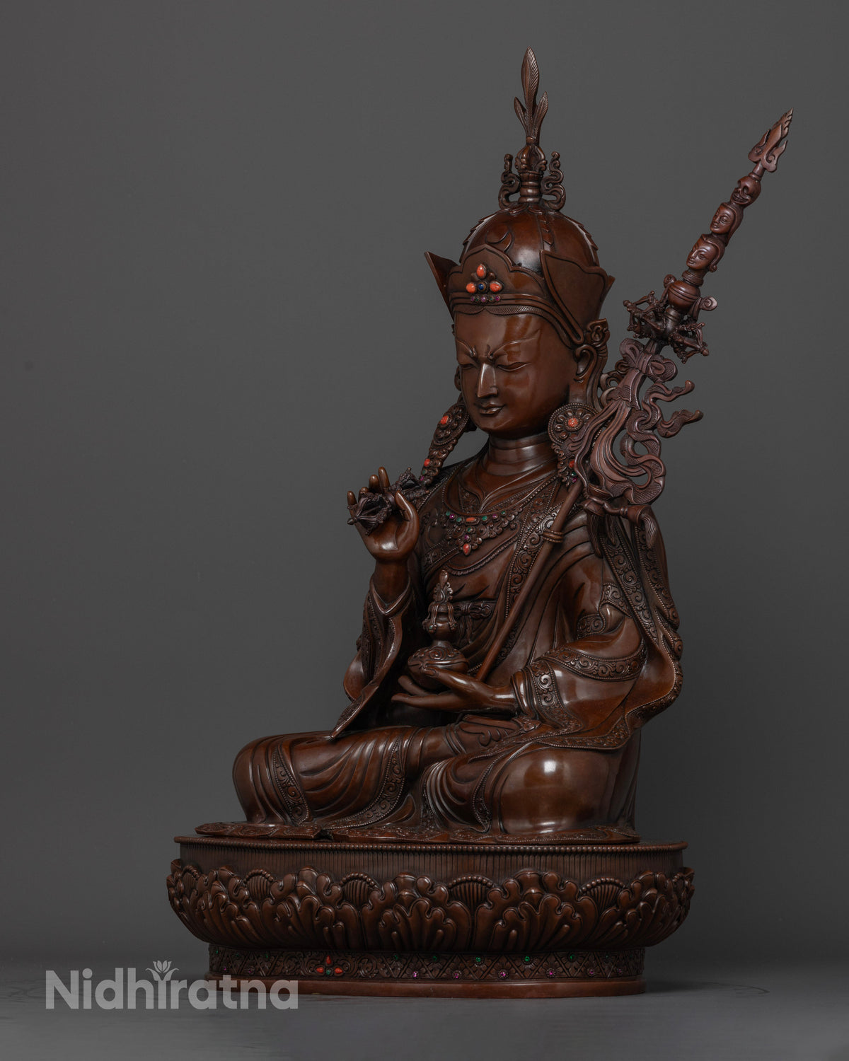Left side view of Tsokye Dorje statue with skull cup and khatvanga staff in oxidized copper