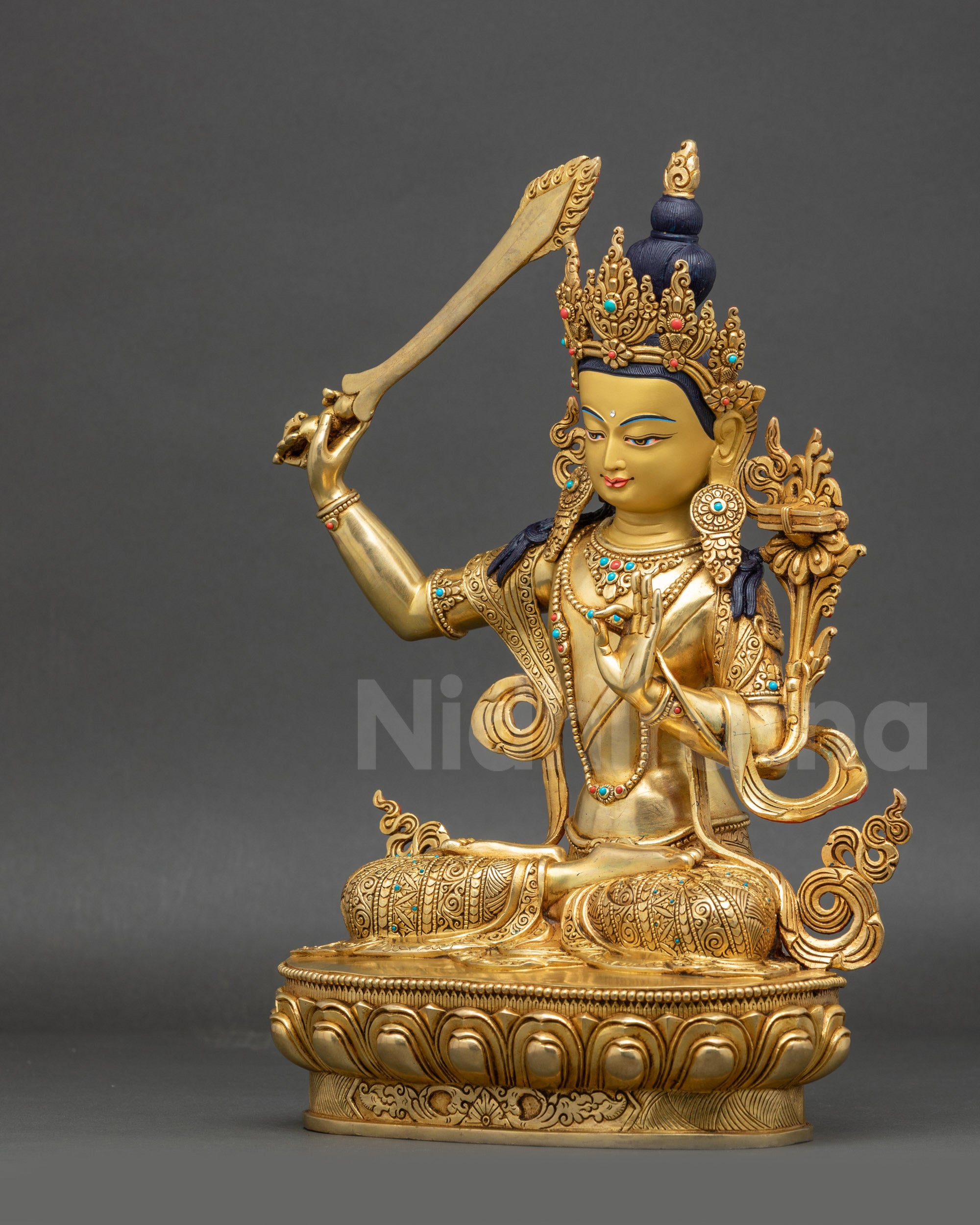 left view side of Manjushri Buddha statue with gold-gilded face and patterned garments