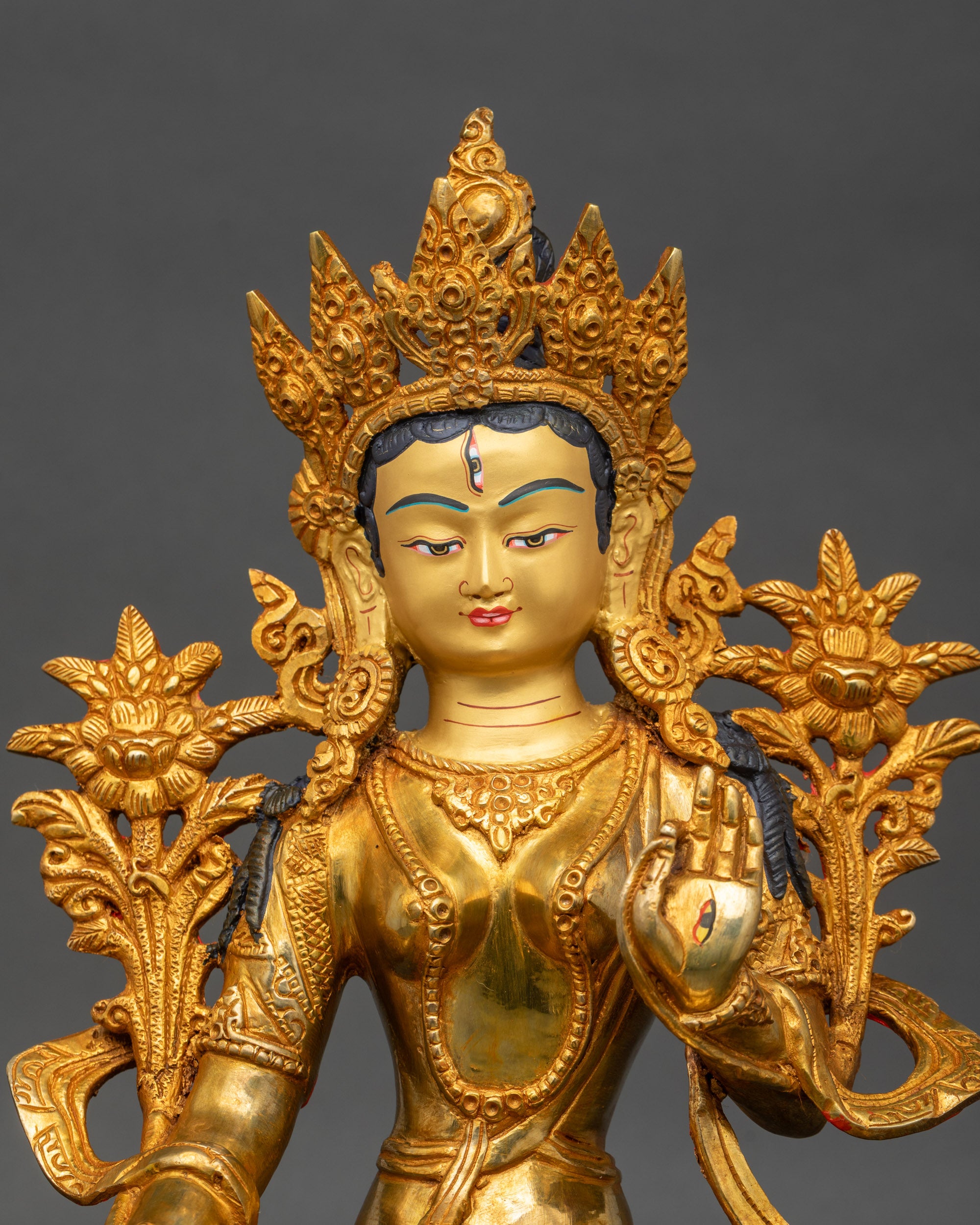 Close-up of White Tara Bodhisattva face with gold paint and seven-eyed detail