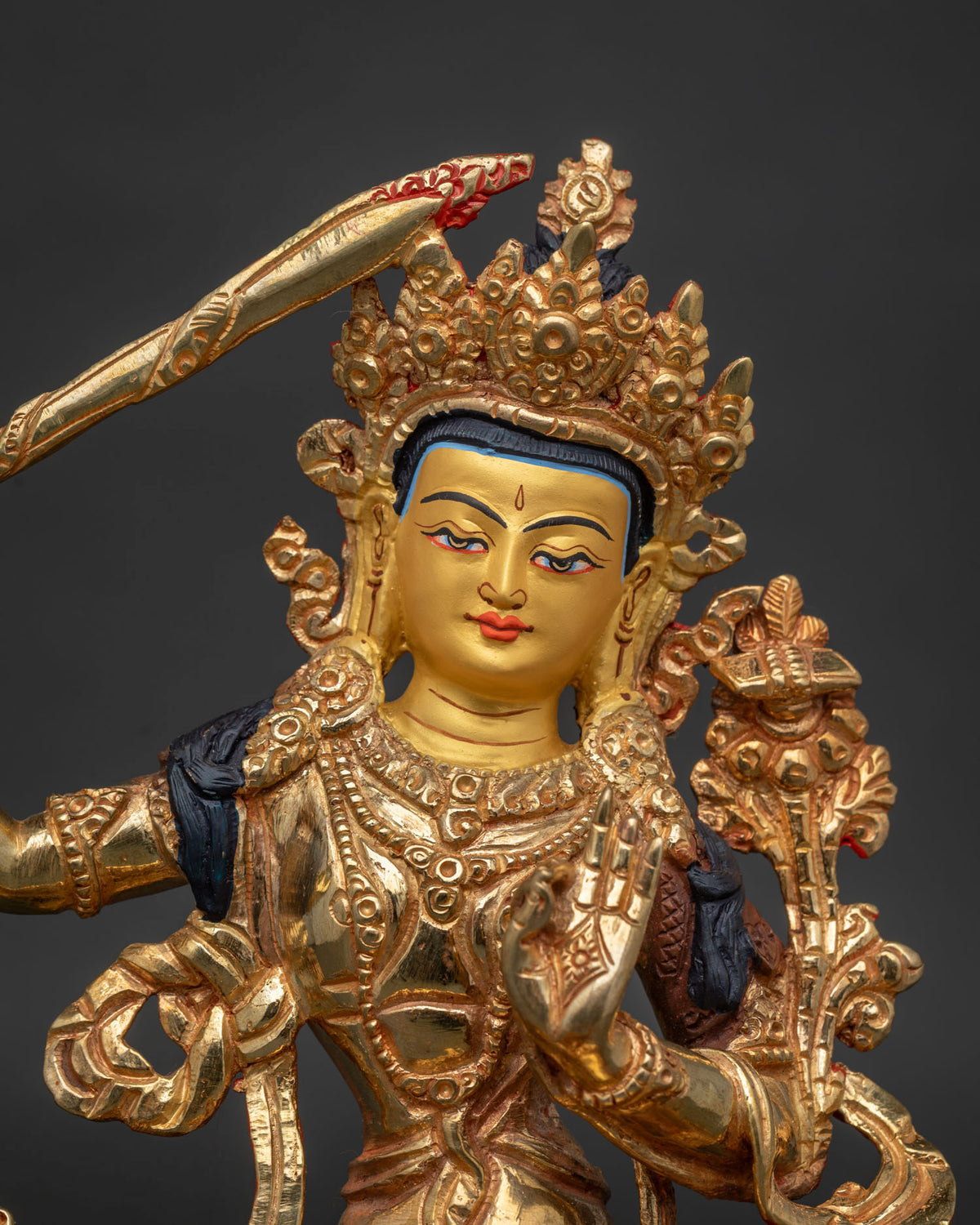 Manjushri Bodhisattva statue with 24K gold painted face seated on an ornate lotus pedestal.