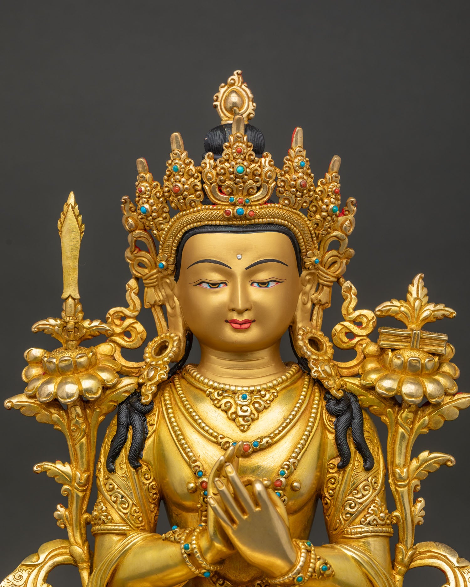 Close up of Manjushri statue showing gold gilding and jeweled crown detail