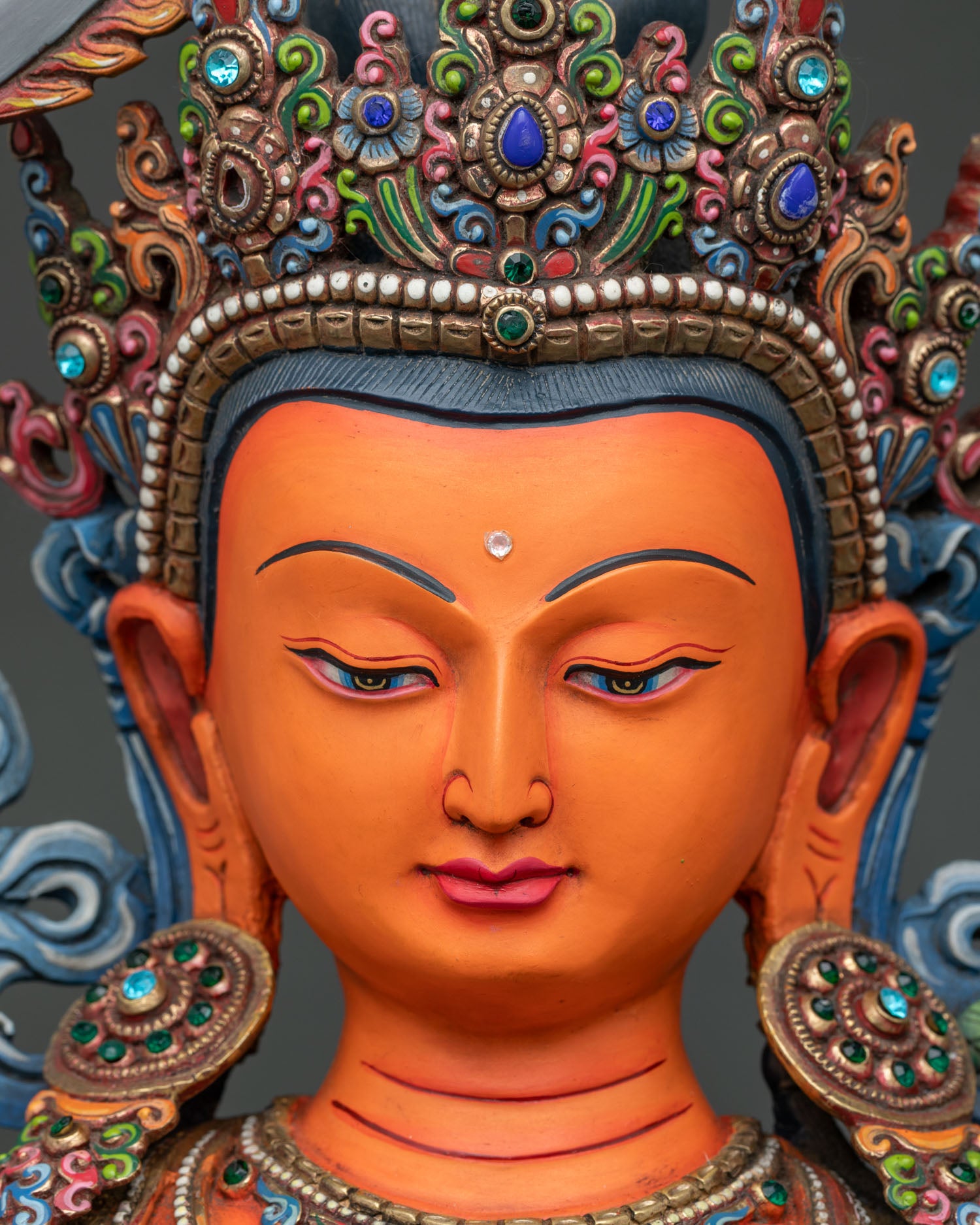 Manjushri statue face close up with serene expression and gold painted features