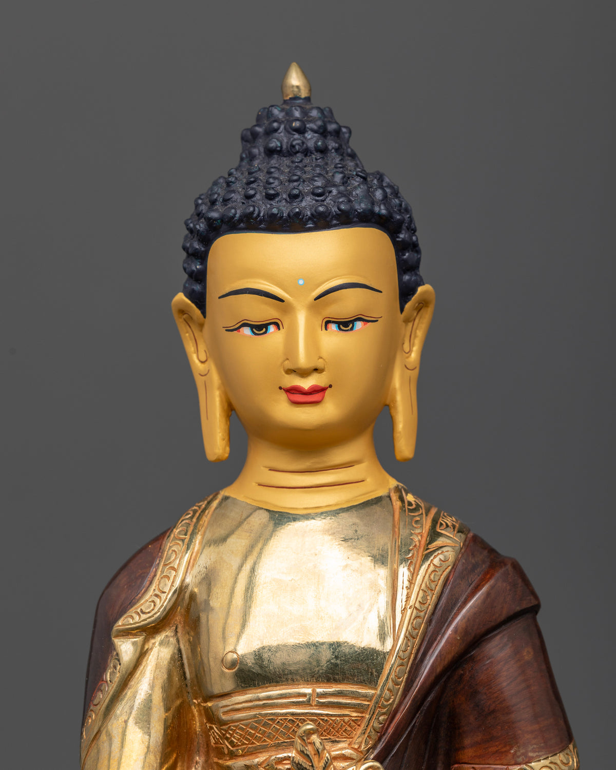 Medicine Buddha statue close up 24K gold painted face healing nectar bowl myrobalan plant details.