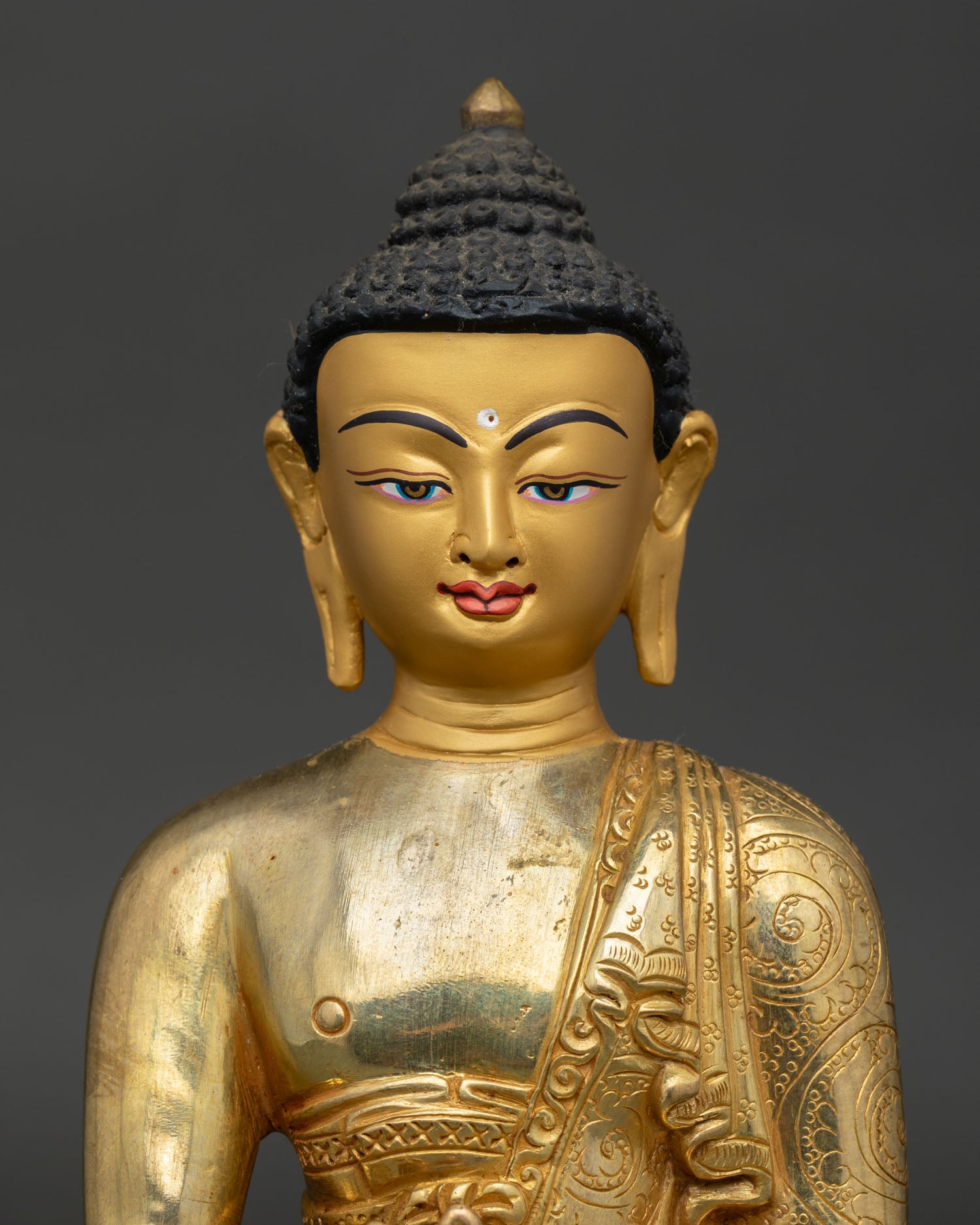 medicine buddha statue close up showing copper body and gold painted details