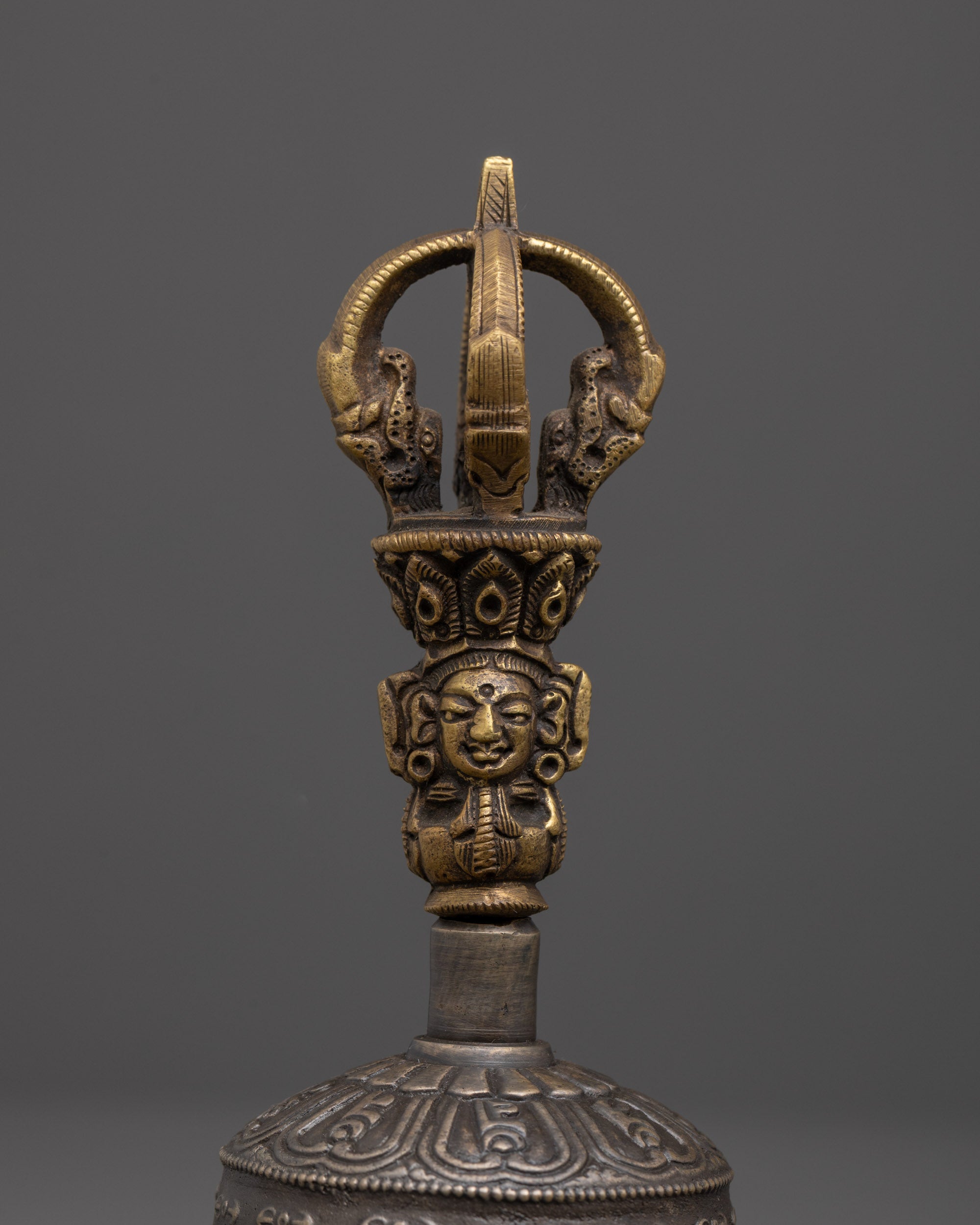 near view of bronze bell handle with brass deity carving for sacred tibetan rituals