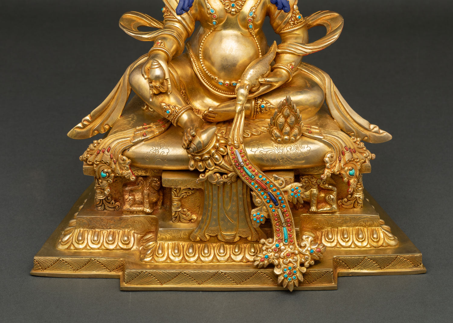 Ornate throne detail of Dzambhala sculpture with snow lions and hand chased metalwork