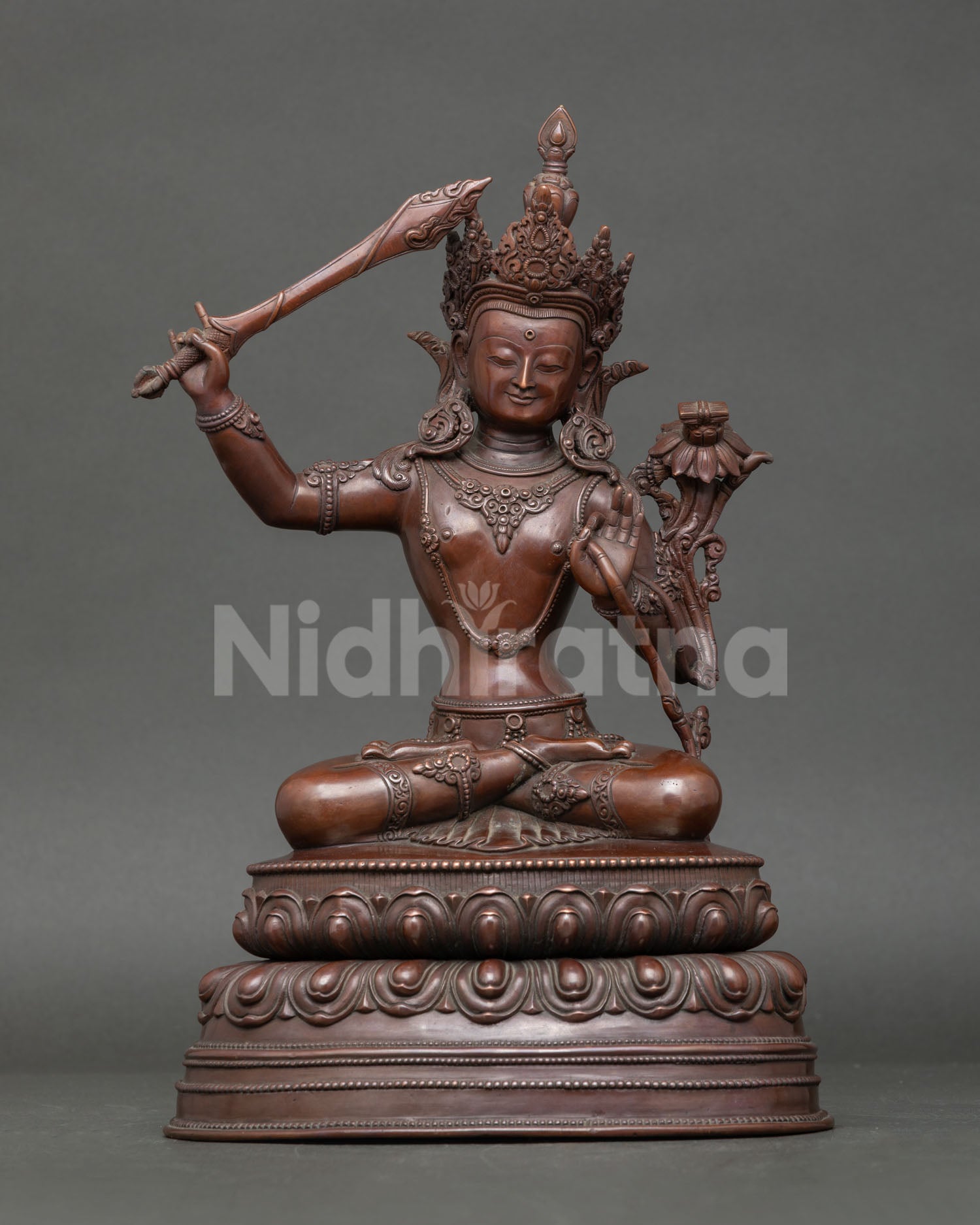 Oxidized copper Manjushri statue seated on lotus throne, holding flaming sword and Utpala flower, Nepalese Buddhist art