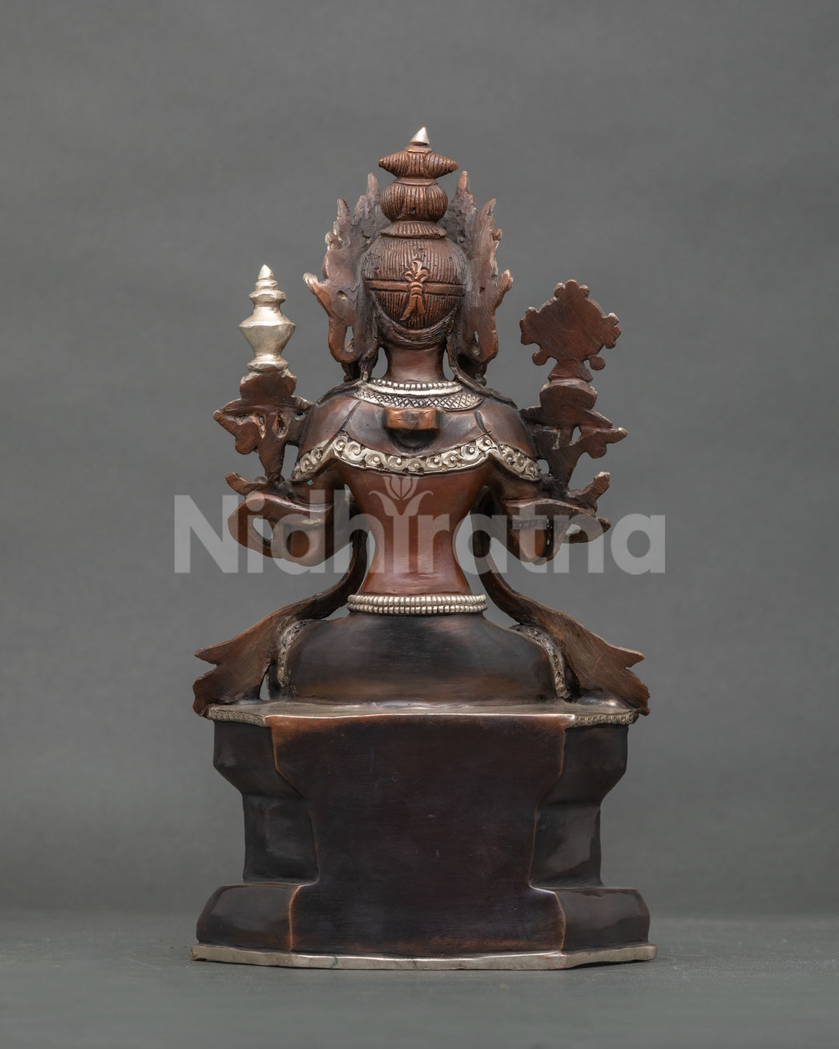 Rear view of oxidized copper Maitreya Buddha statue showing ornate finial and throne base