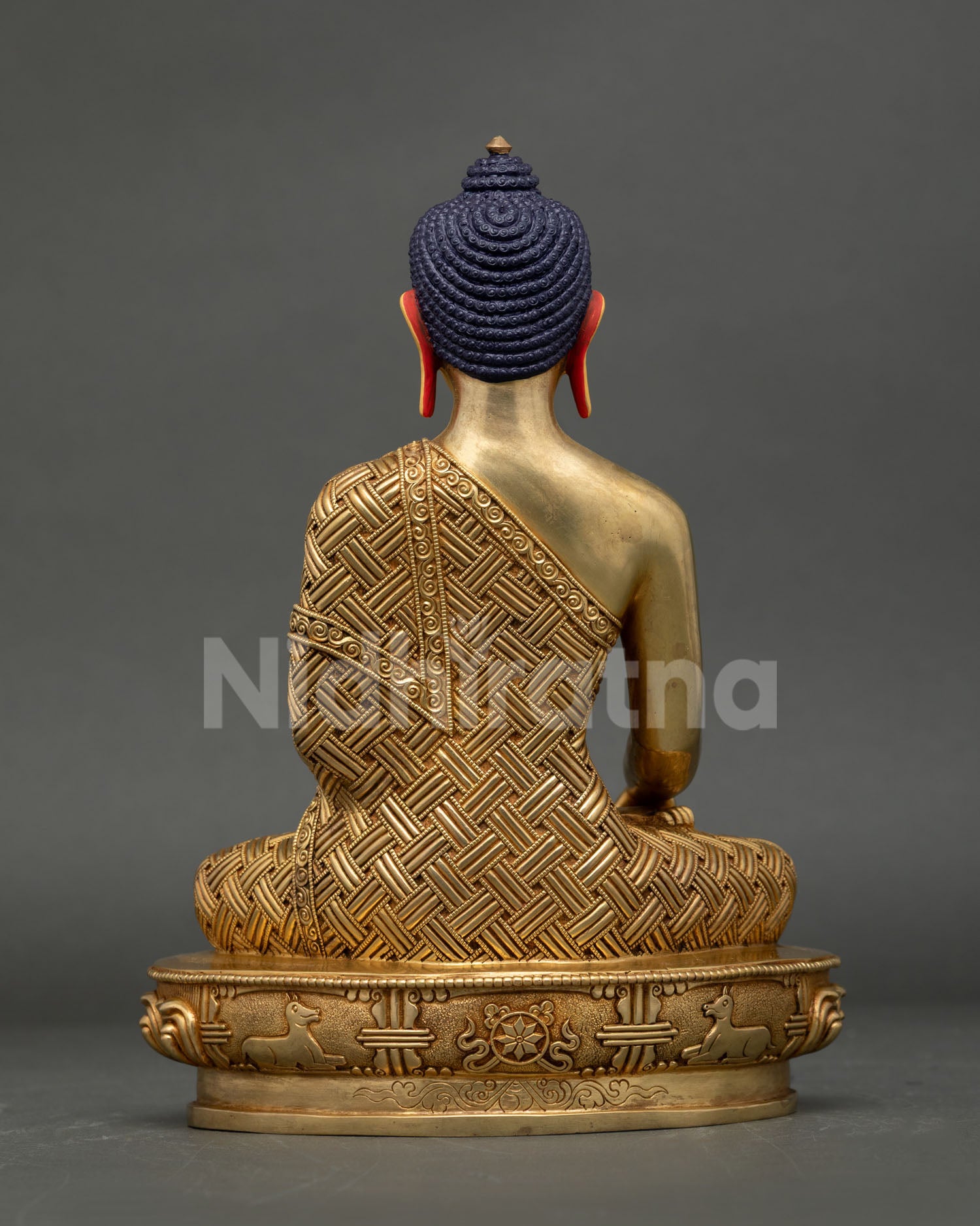 Rear view of Shakyamuni Buddha statue showing detailed craftsmanship, robe engravings and lotus base