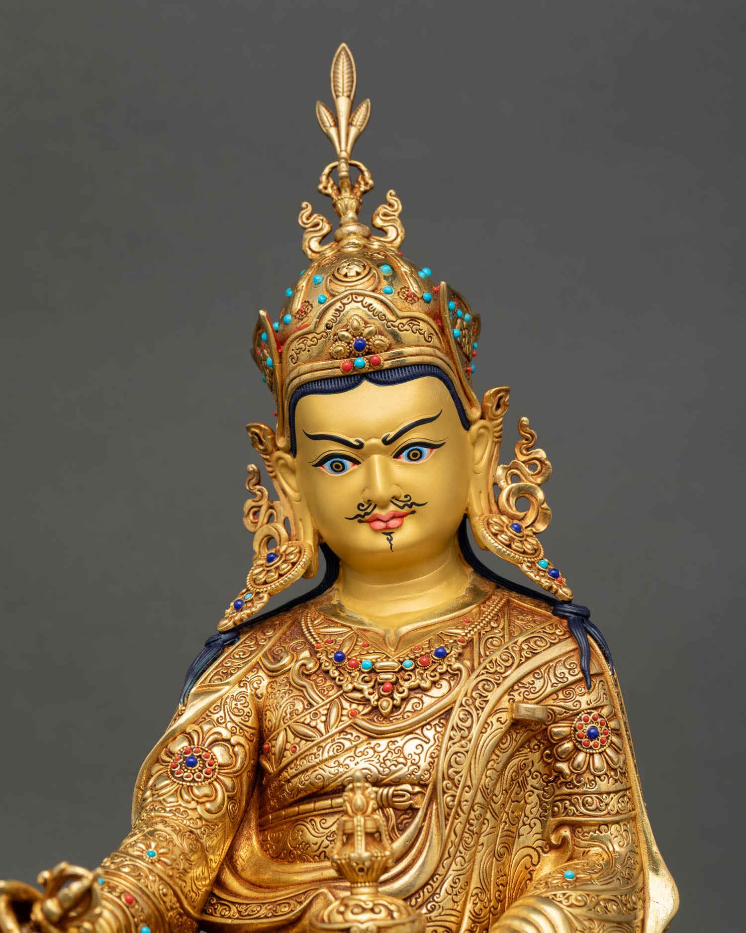 Regular close-up of Guru Rinpoche statue showing intricate metalwork and lotus base