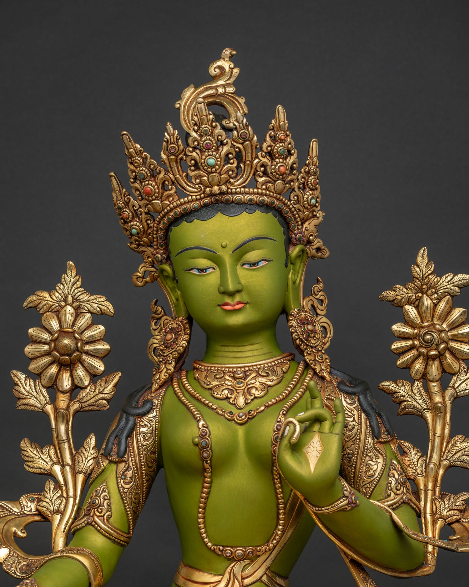 Regular close up of Green Tara statue showing ornate jewelry lotus flowers and gold gilding
