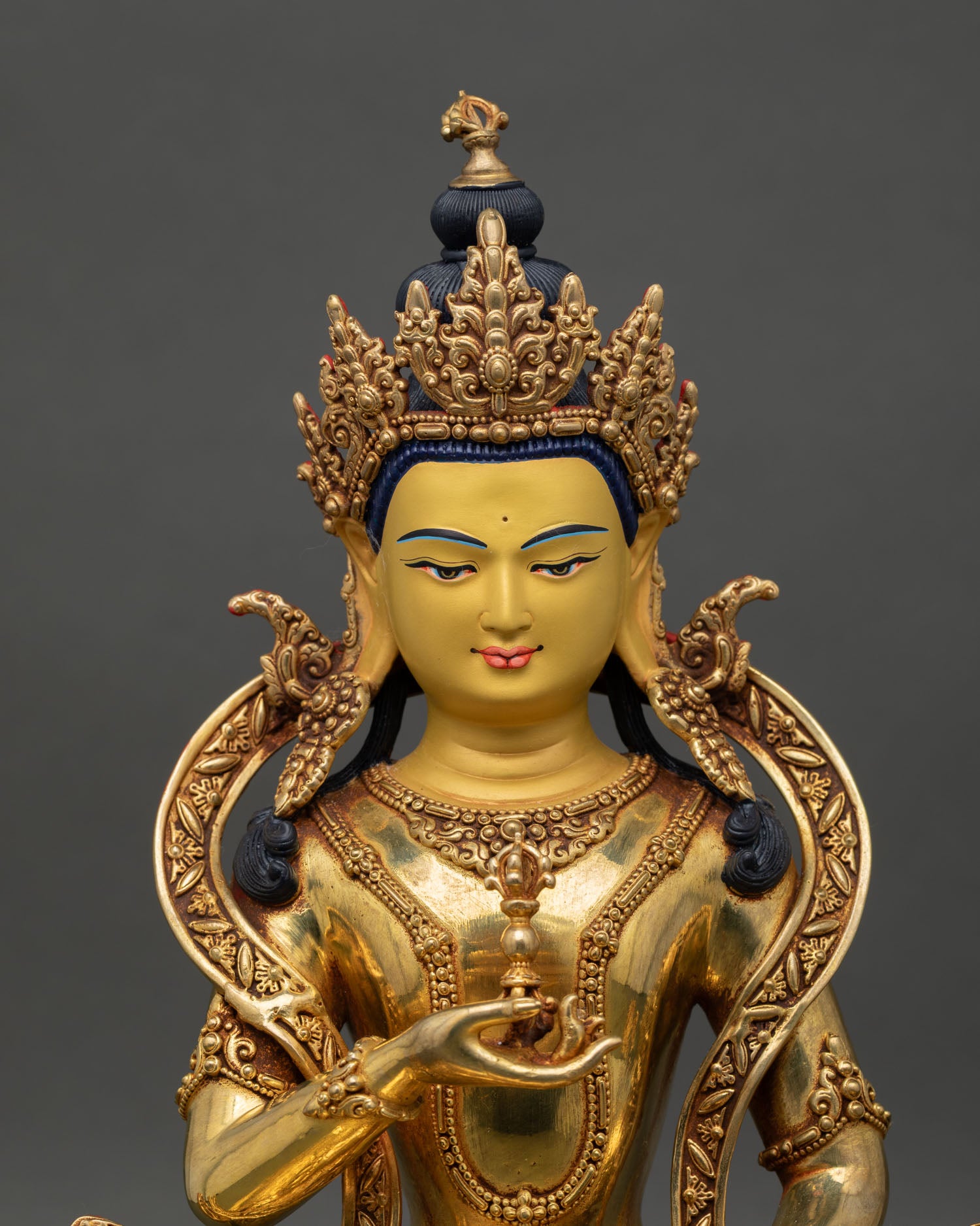 regular close-up of vajrasattva statue showing gold gilded details and seated posture