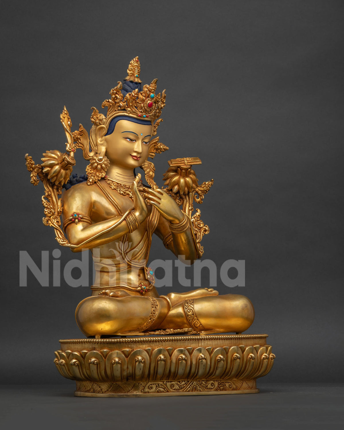 Right side view of gold gilded Manjushri statue seated on a lotus base