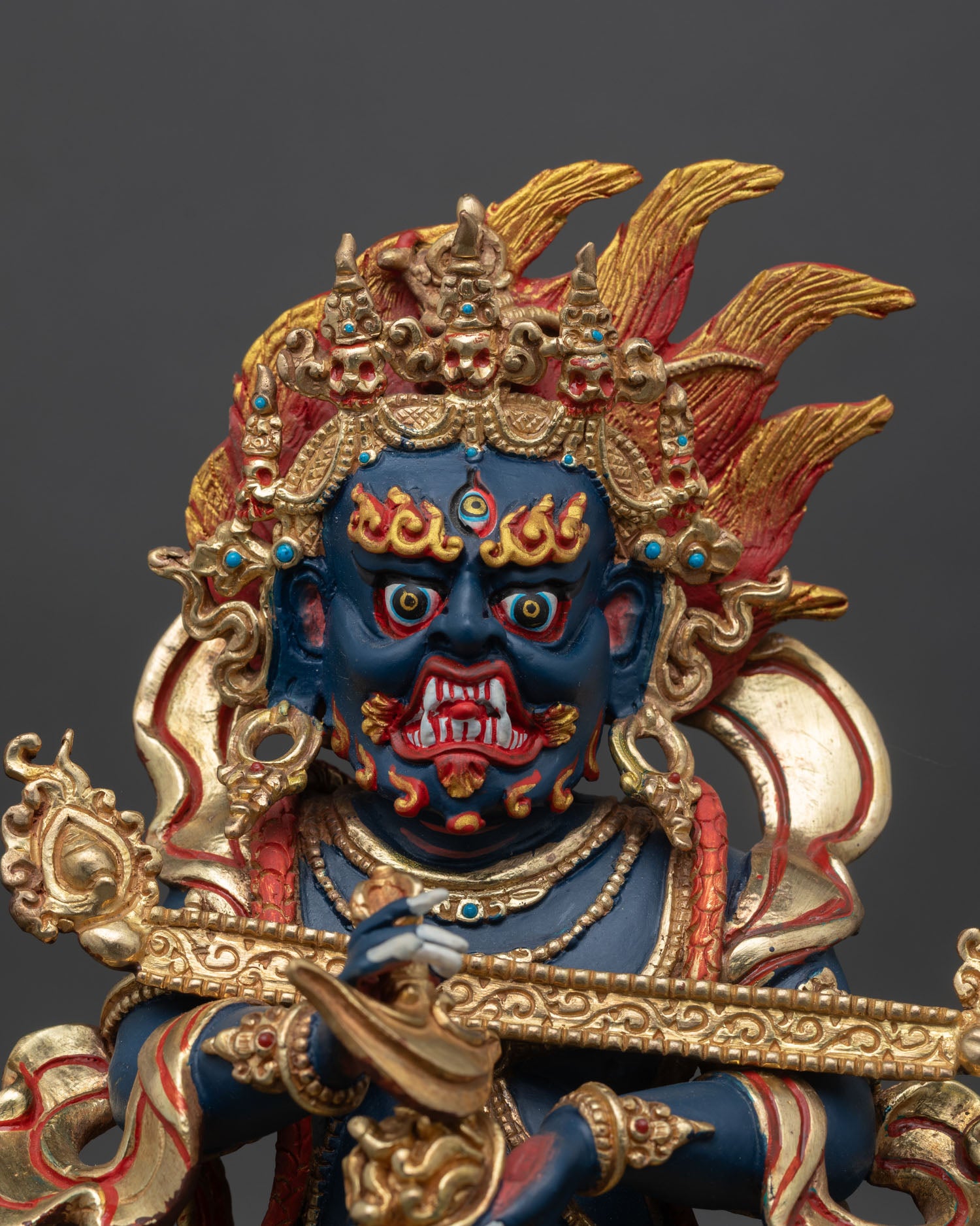 Sakya Mahakala close up fierce guardian face with hand painted details gold gilded copper Vajrayana protector deity statue.