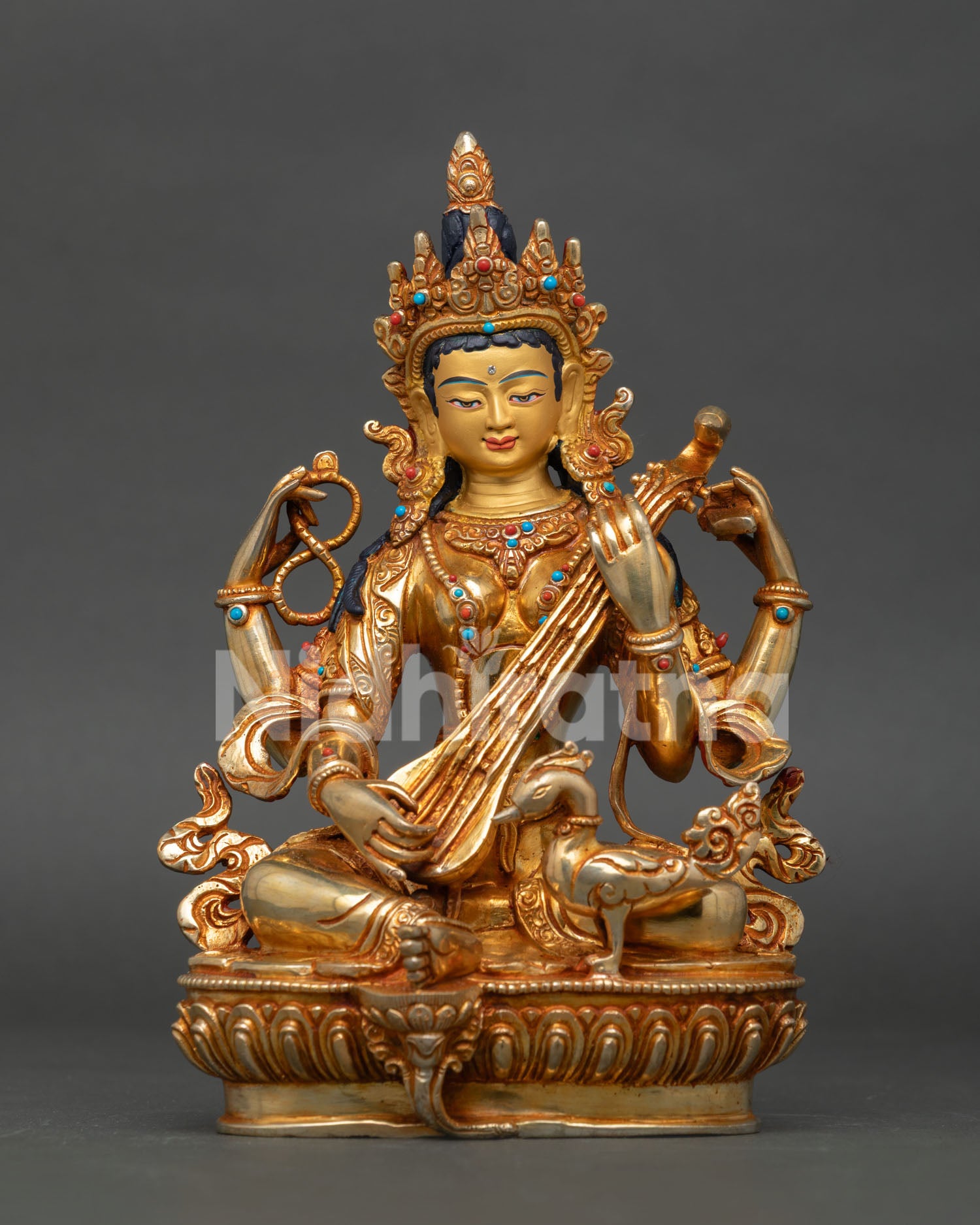 Saraswati statue seated on lotus pedestal holding veena pustaka and rosary mala.