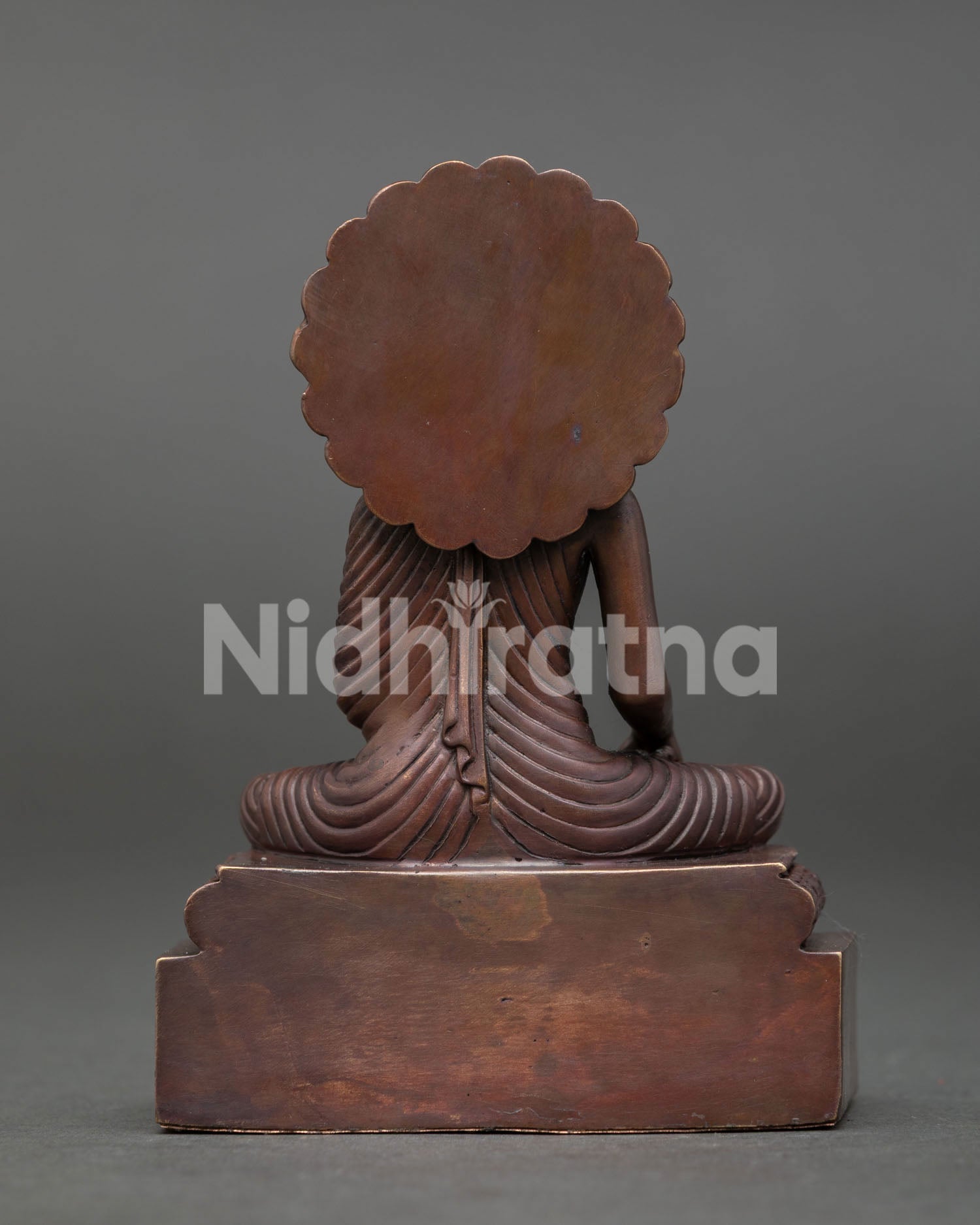 Shakyamuni Buddha sculpture with ornate pedestal halo design and oxidized copper finish representing enlightenment and wisdom.