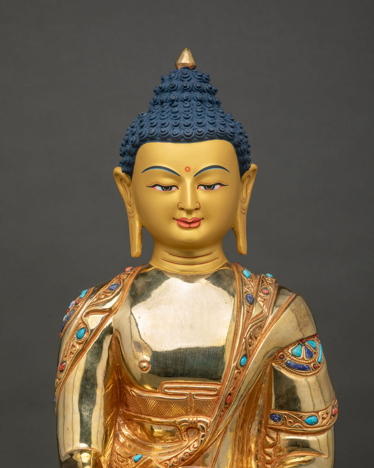 Shakyamuni Buddha statue 24k gold painted face turquoise lapis coral close up.