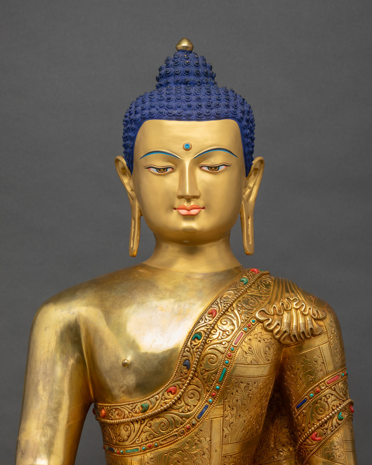 Shakyamuni Buddha statue close up showing gold gilded torso and gemstone inlaid monastic robe