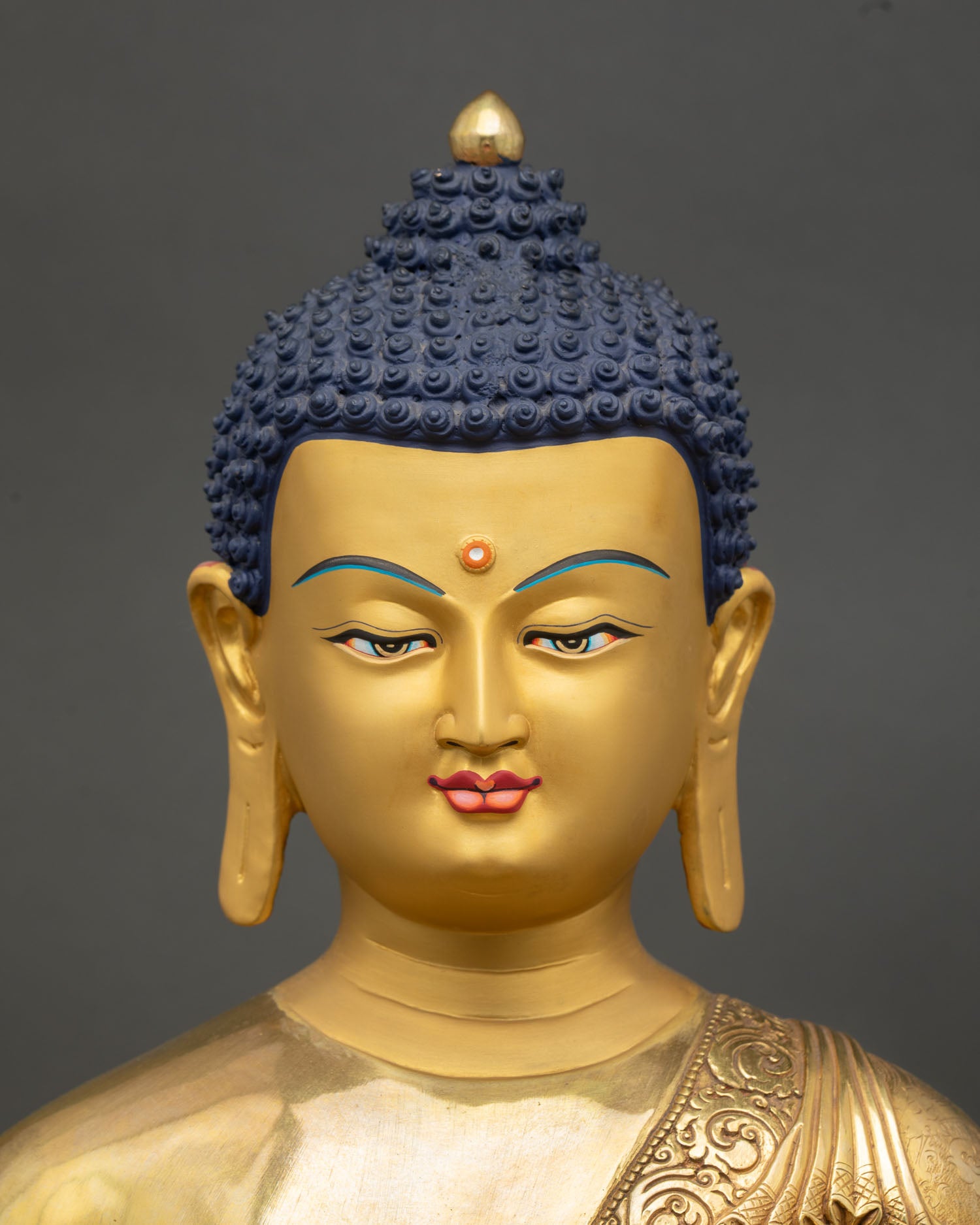 Face close up Shakyamuni Buddha statue, serene enlightened expression with 24K gold painted facial features