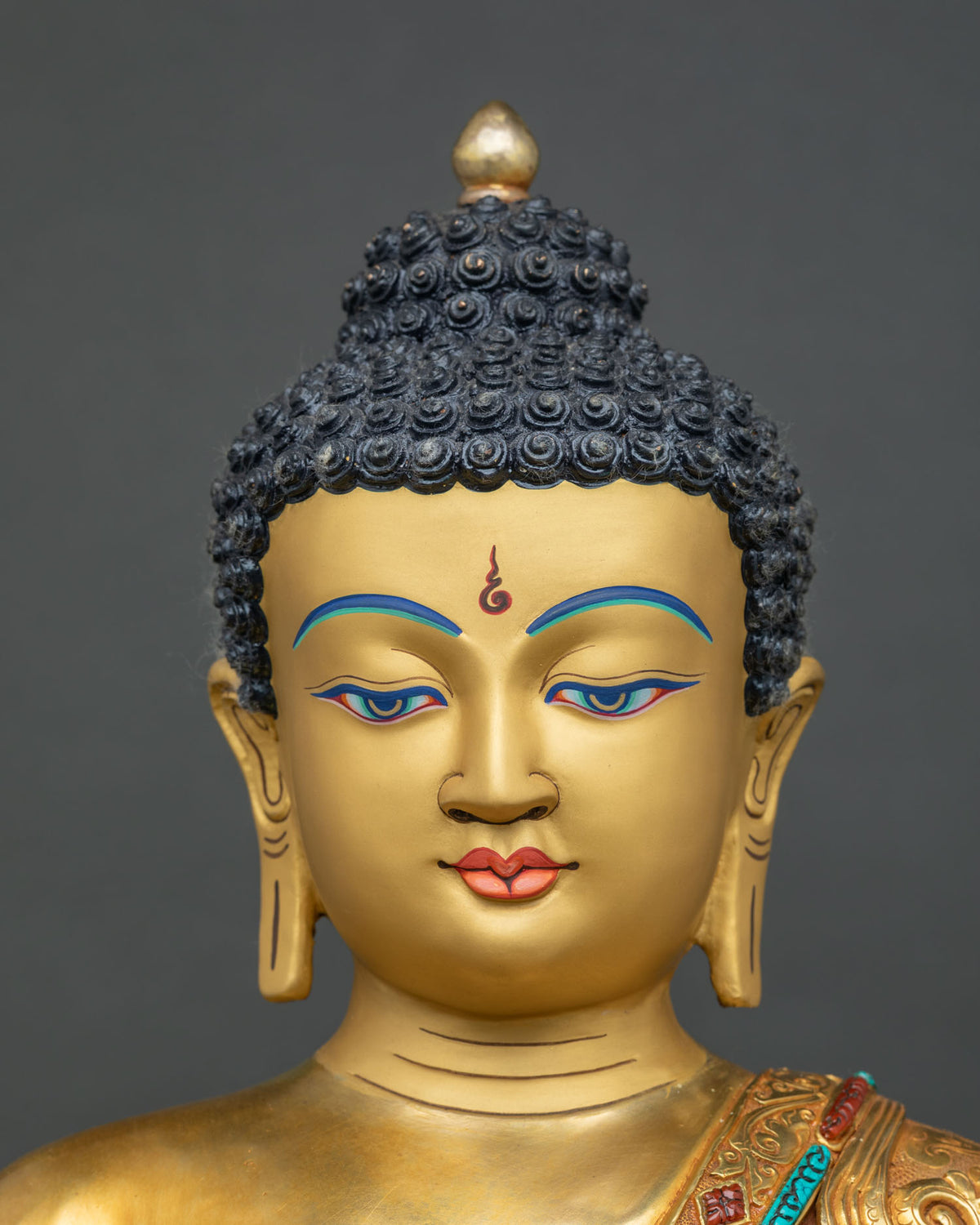 Shakyamuni Buddha statue face close-up with painted eyes, ushnisha and curled hair