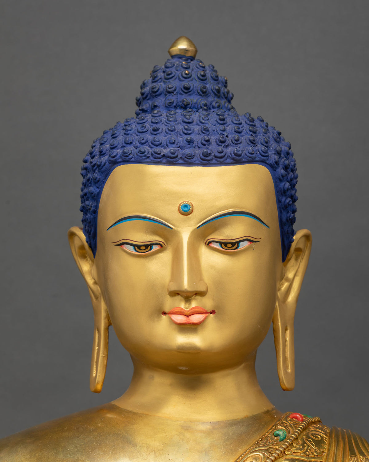 Shakyamuni Buddha statue face close up with serene downcast eyes and deep blue hair