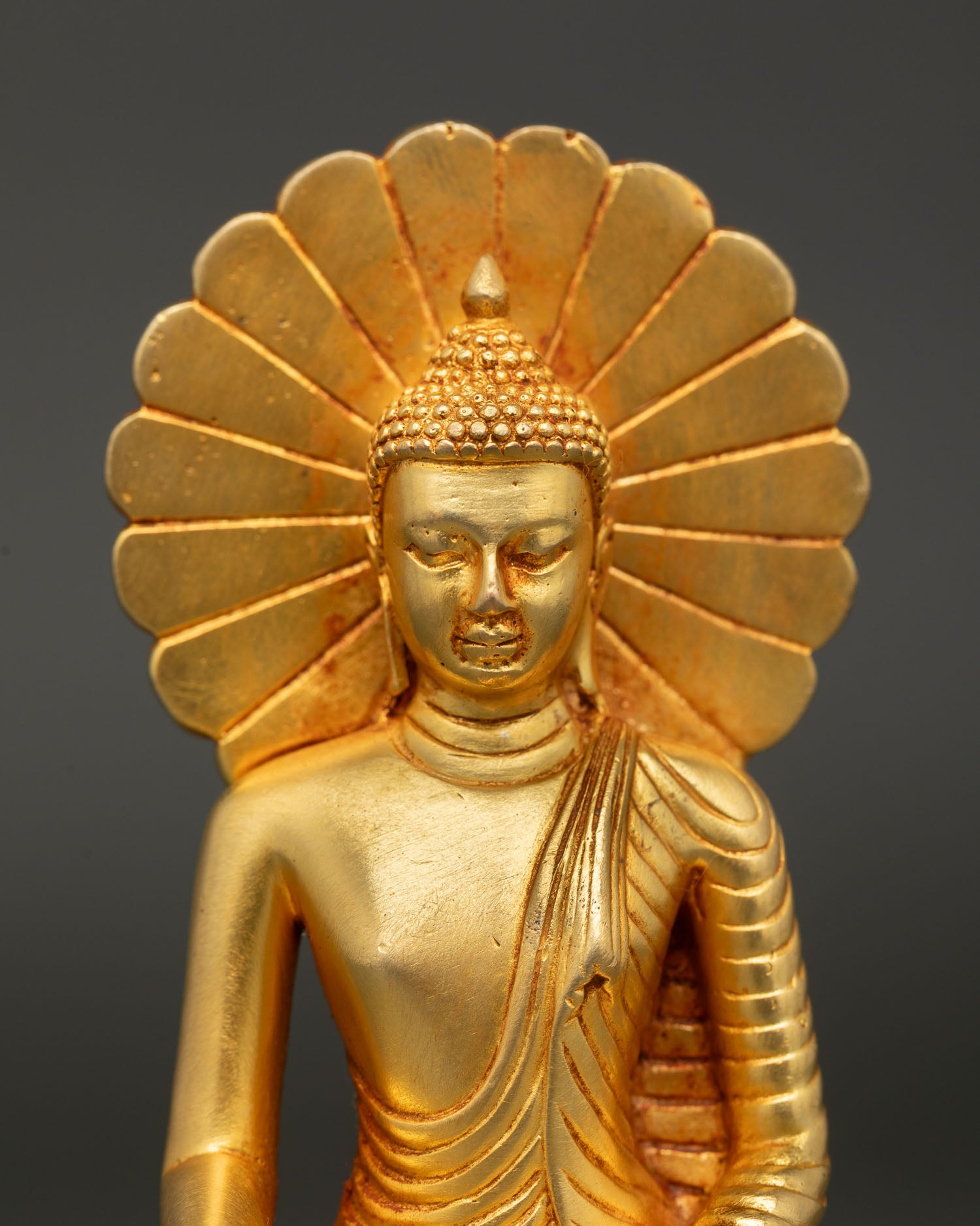 Shakyamuni Buddha statue showing gold painted face intricate details and Nepalese craftsmanship.