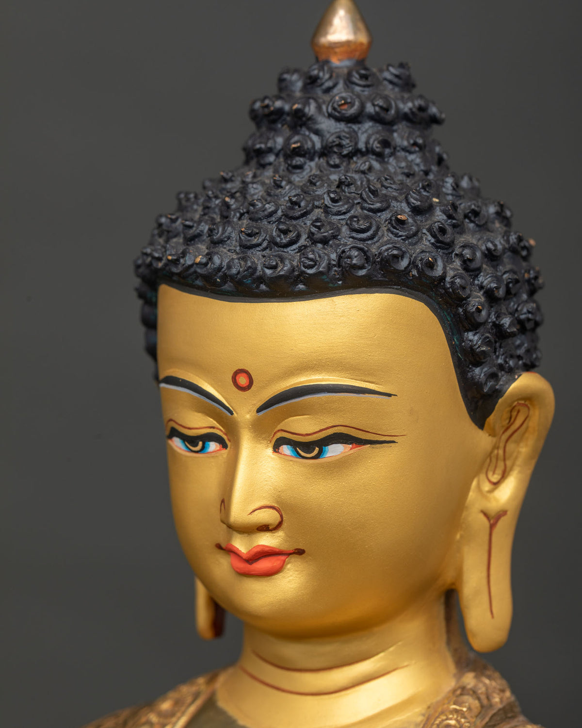 Shakyamuni Buddha statue side face close up serene expression and gold details.