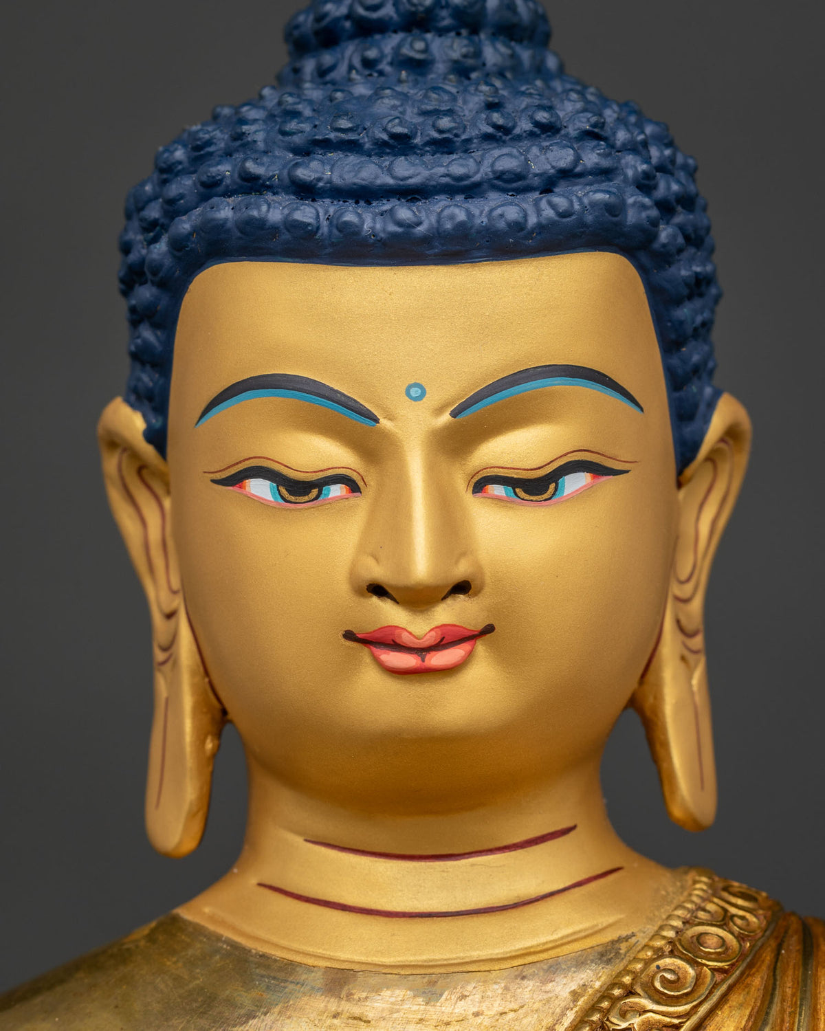 Shakyamuni Buddha statue with 24K gold painted face and blue eyes.