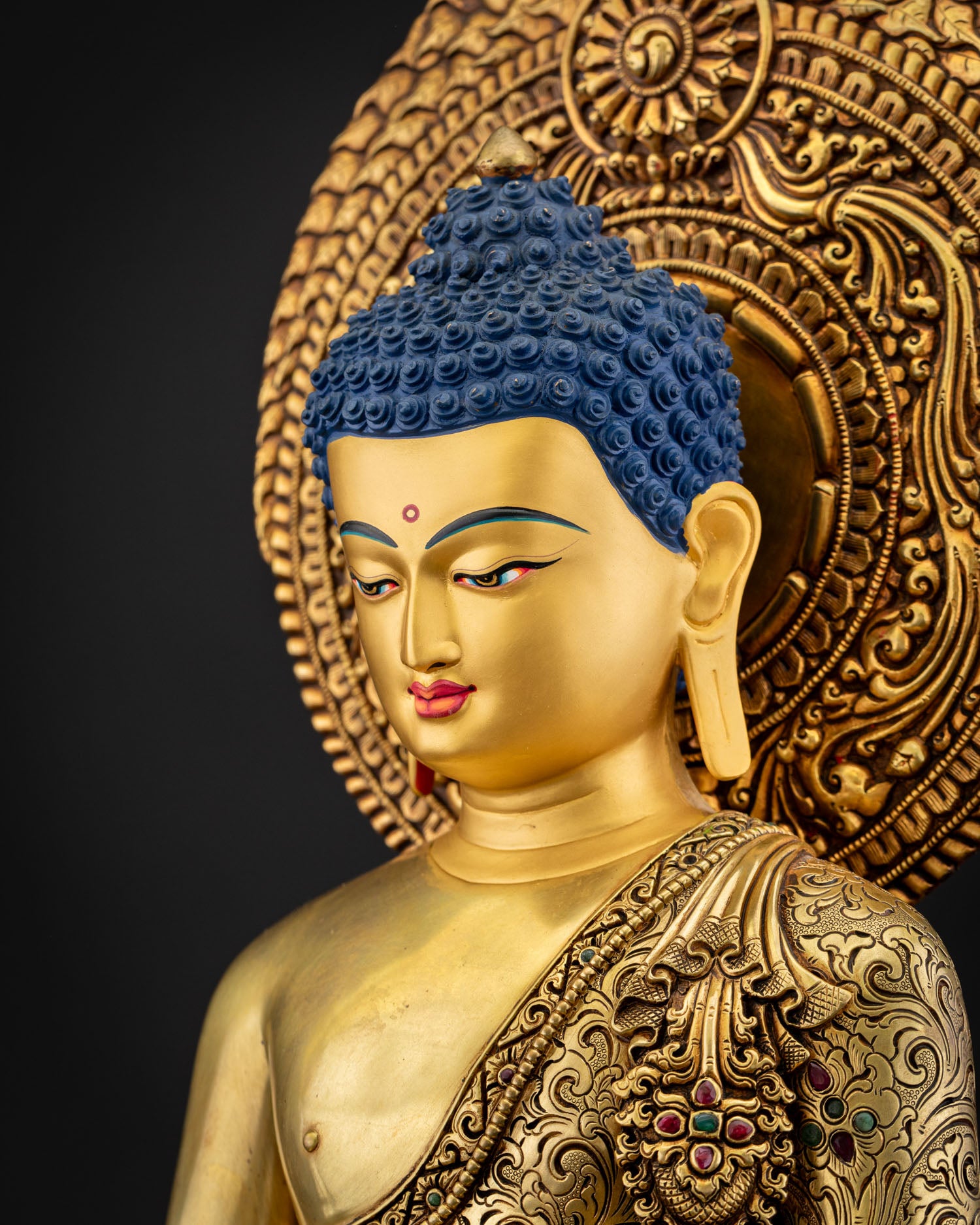 Side close‑up of Amitabha Buddha statue highlighting repoussé detailing and monastic robe carvings