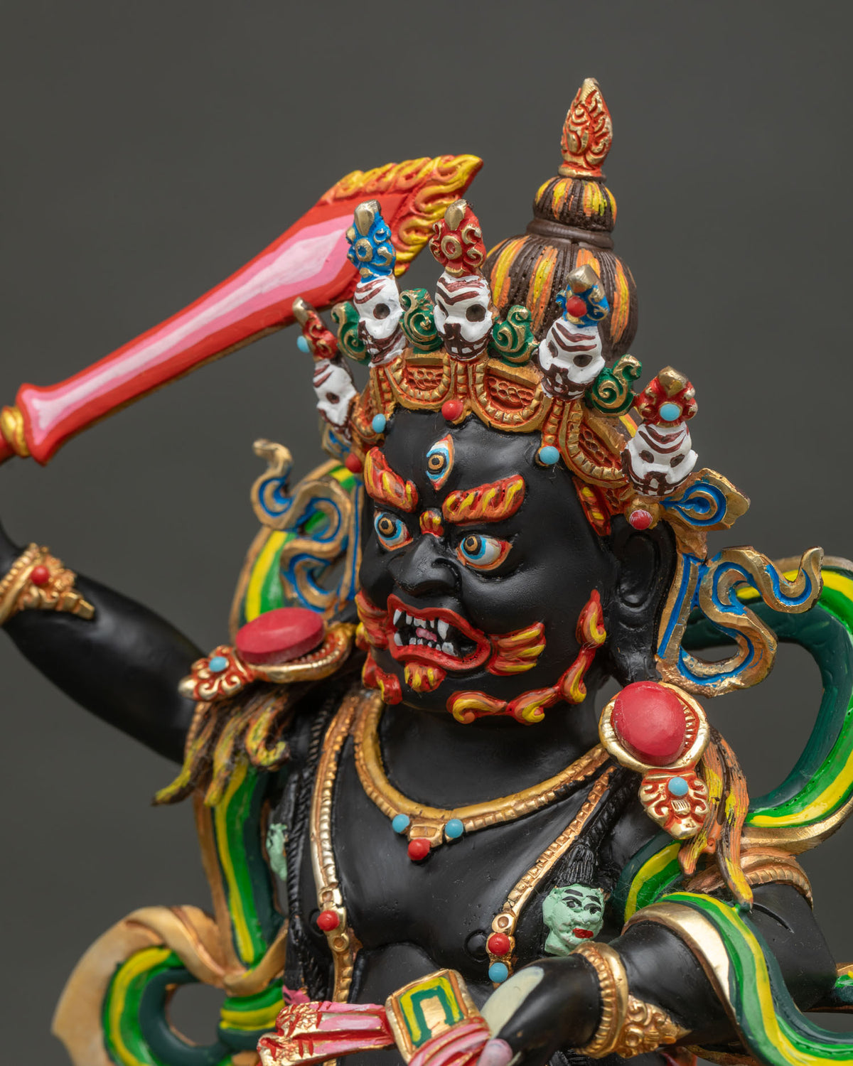 Side close-up of Black Manjushri statue detailing sword, ornaments, and gold fire-gilded halo