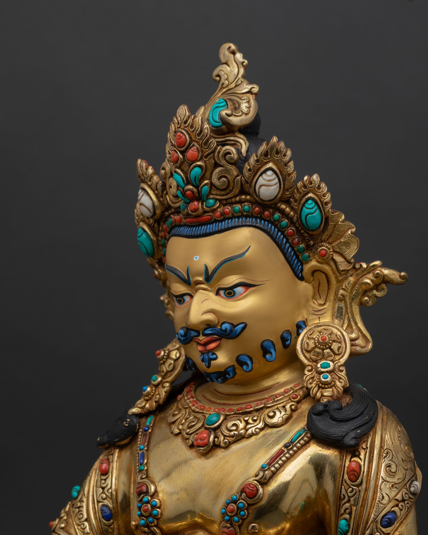 side close up of dzambhala statue with ornate halo and detailed craftsmanship