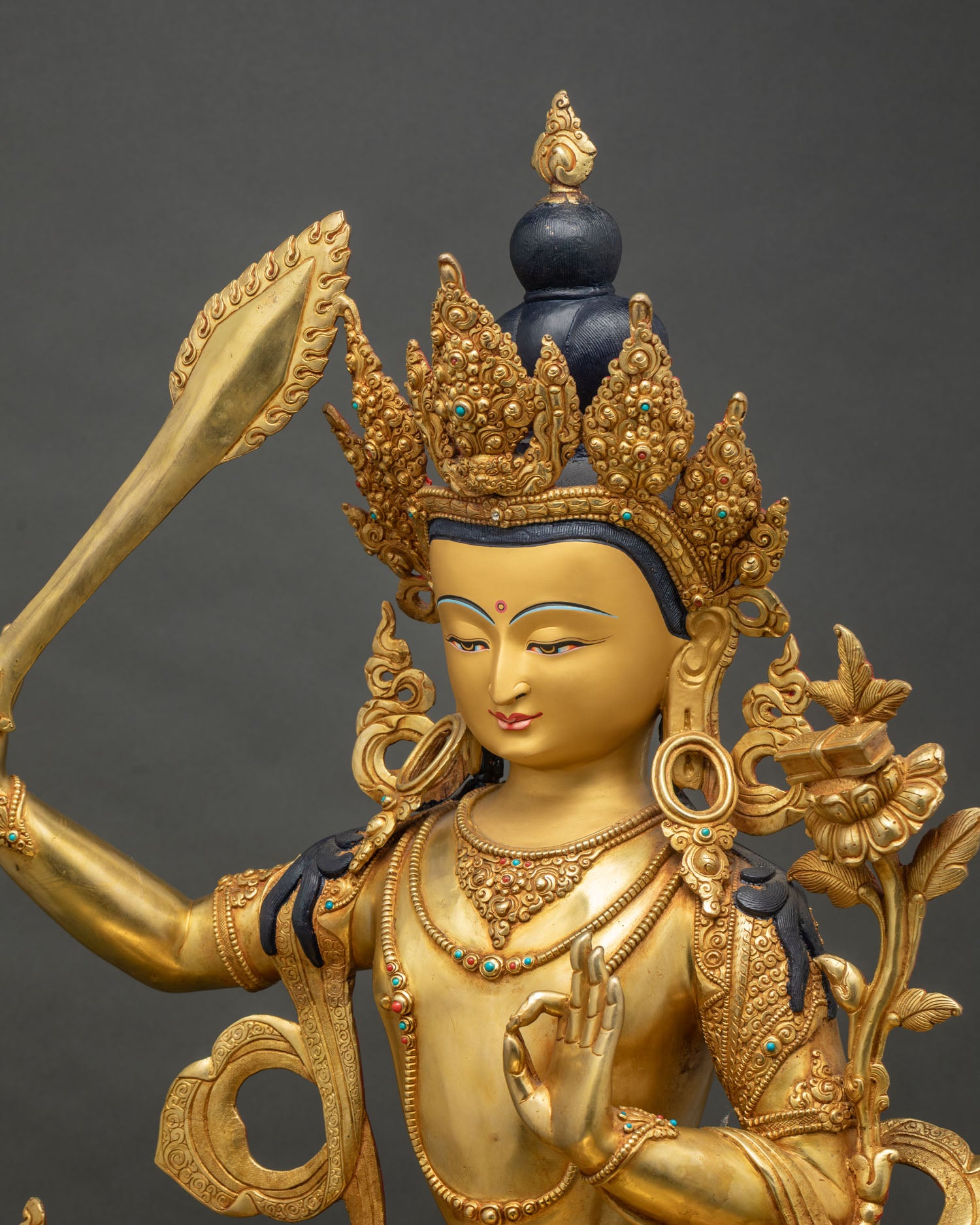 Side close up of Manjushri statue detailing crown and flaming sword, Nepal