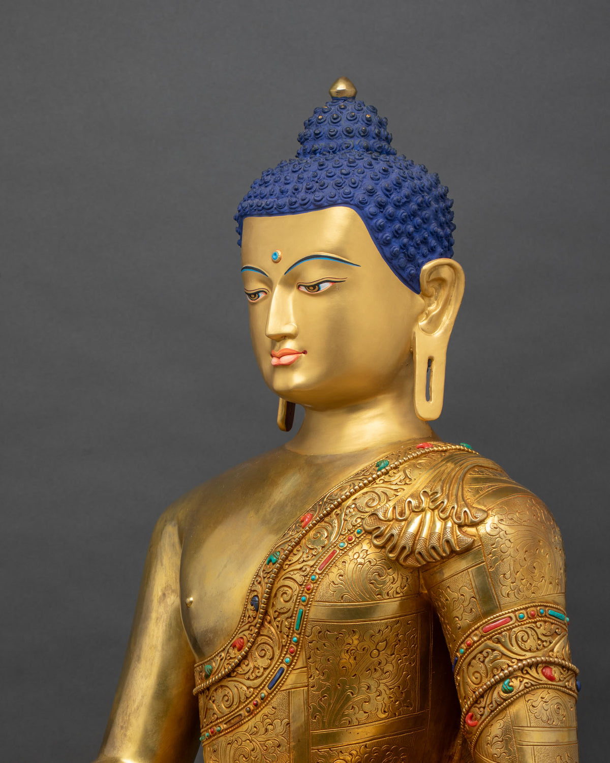 Side close up of Shakyamuni Buddha statue robe with hand-chased scrollwork and gemstone inlay