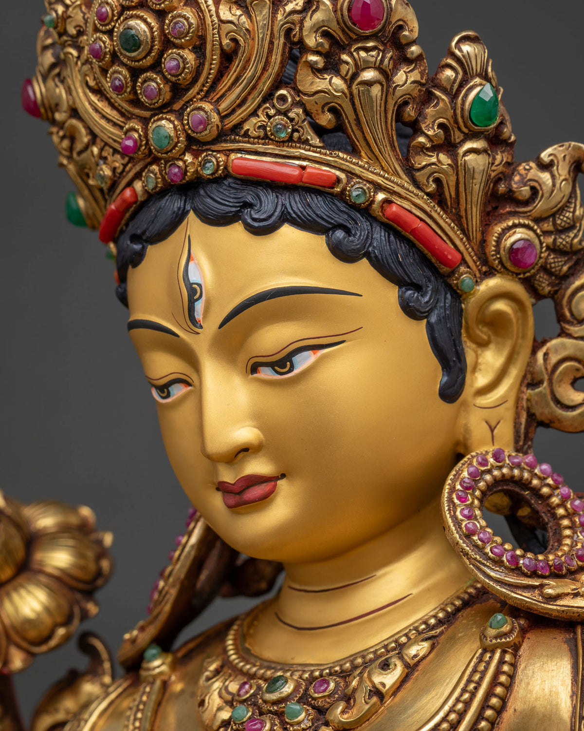 Side close up of White Tara Statue's serene gold-painted face and crown detailing