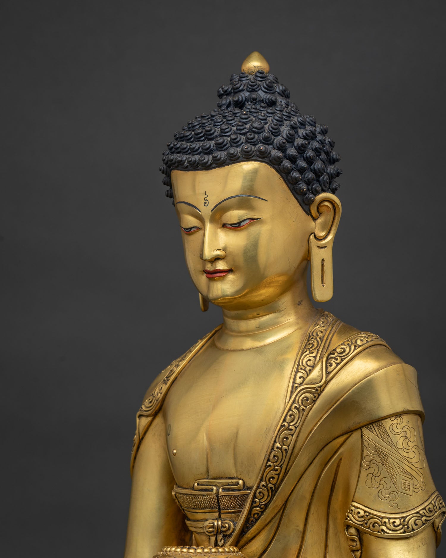 side detail close up of 24k gold shakyamuni buddha statue hand incised robe nepal