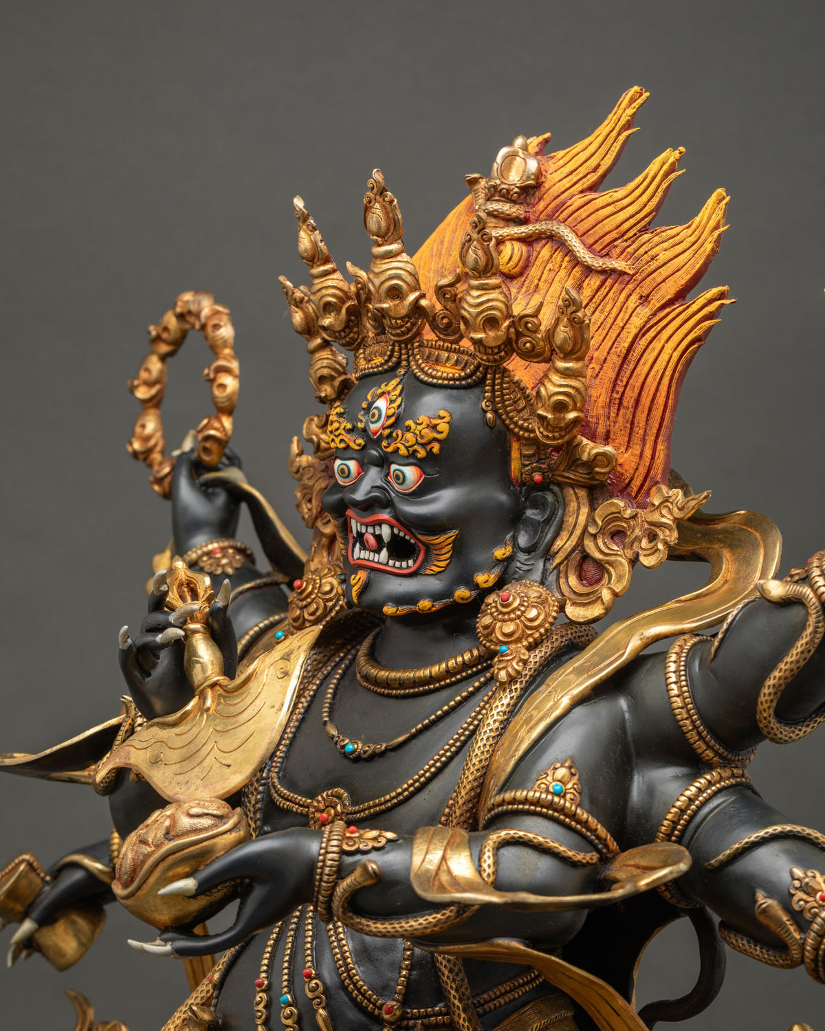 Side detail of Shadbhuja Mahakala statue showing hand-chased serpent ornaments and gold gilding