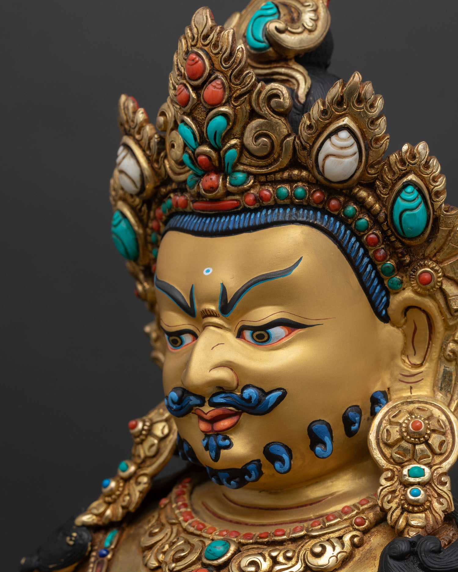 side close up of dzambhala statue with ornate halo and detailed craftsmanship
