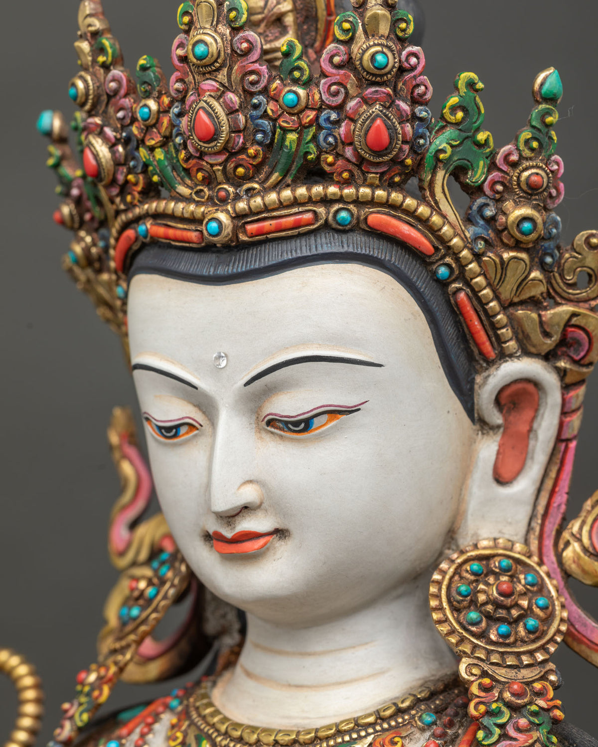 Side profile close up of calm face and crown on Chenrezig Buddha