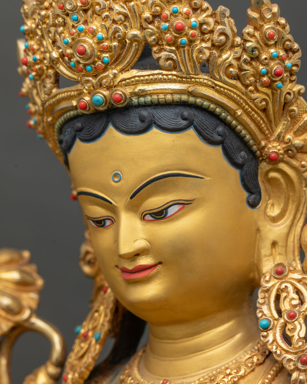 Side profile close up of Green Tara statue face and ornate jeweled crown